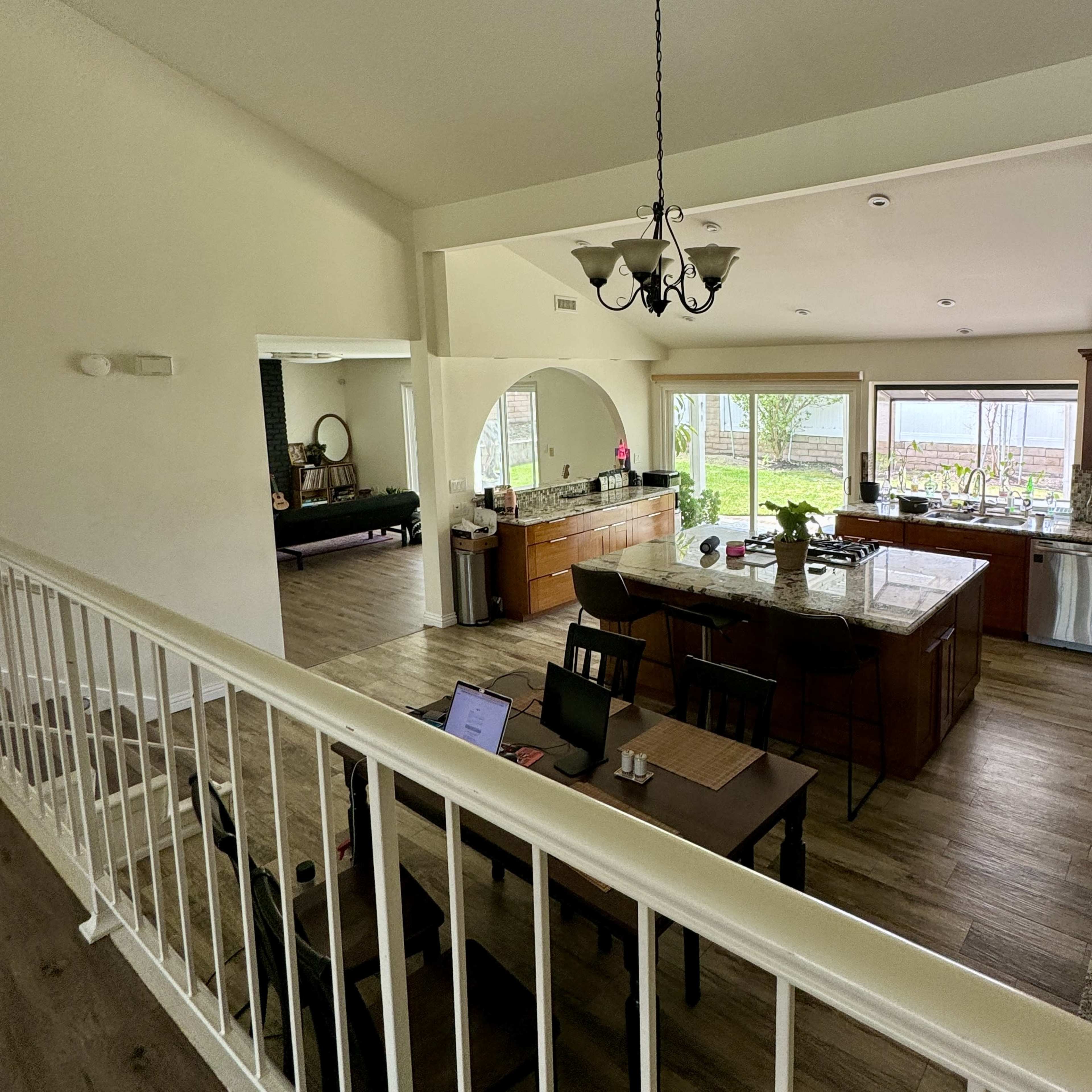 A spacious kitchen and dining area feature wooden cabinetry, granite countertops, and large windows allowing natural light.