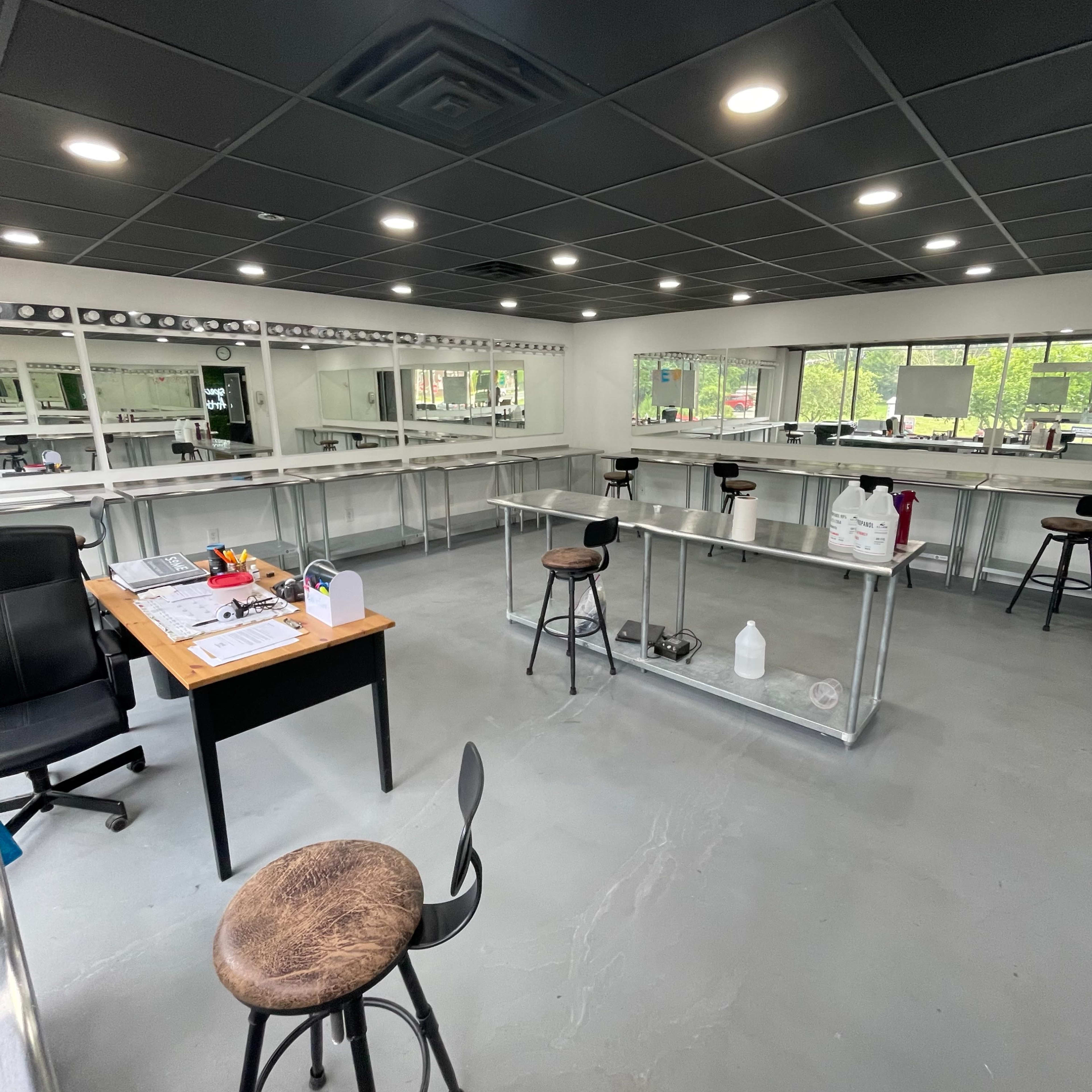 A spacious, well-lit lab or workspace featuring multiple tables and a desk with a chair.