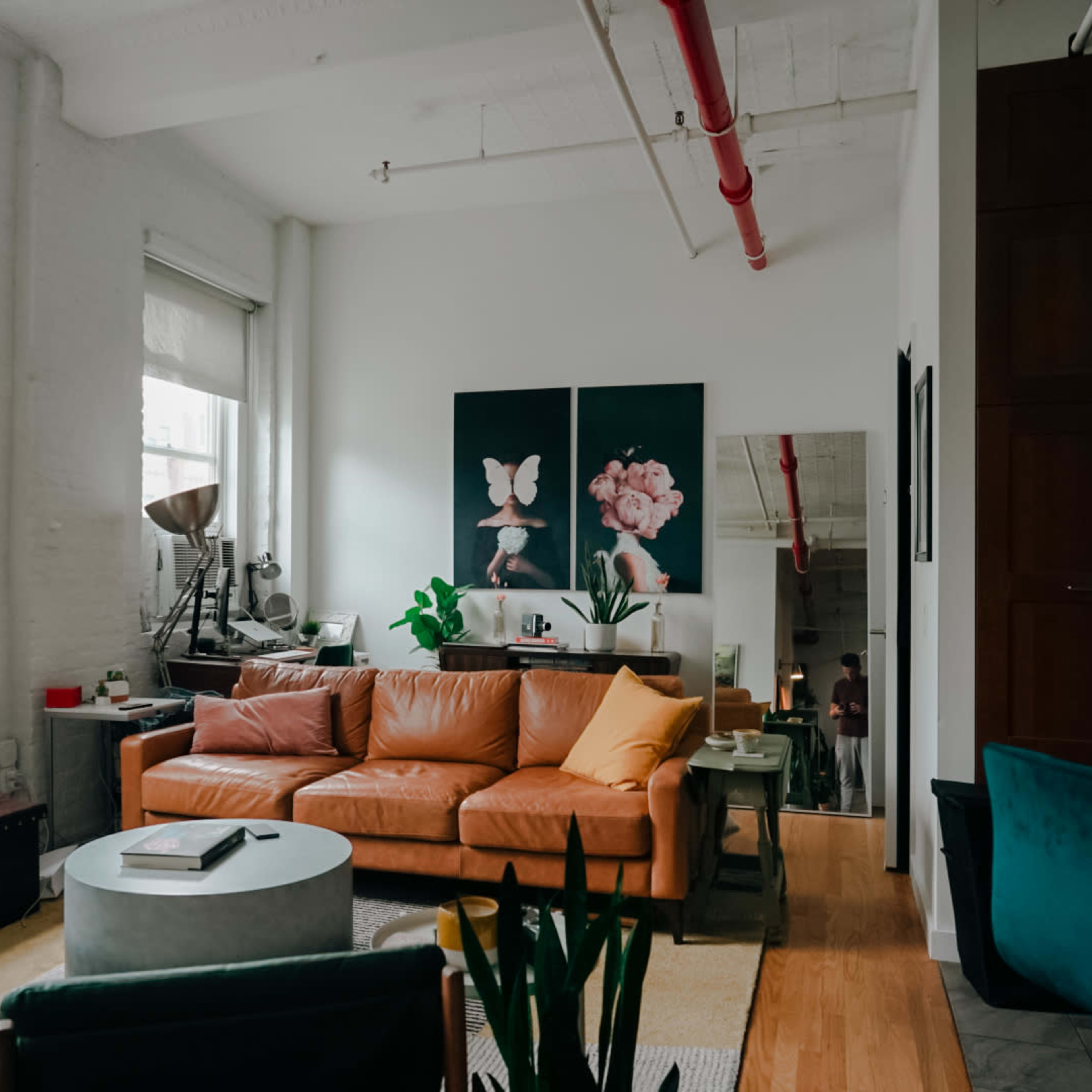 A well-lit living room featuring a brown leather sofa, a round coffee table, and large artwork on the wall.