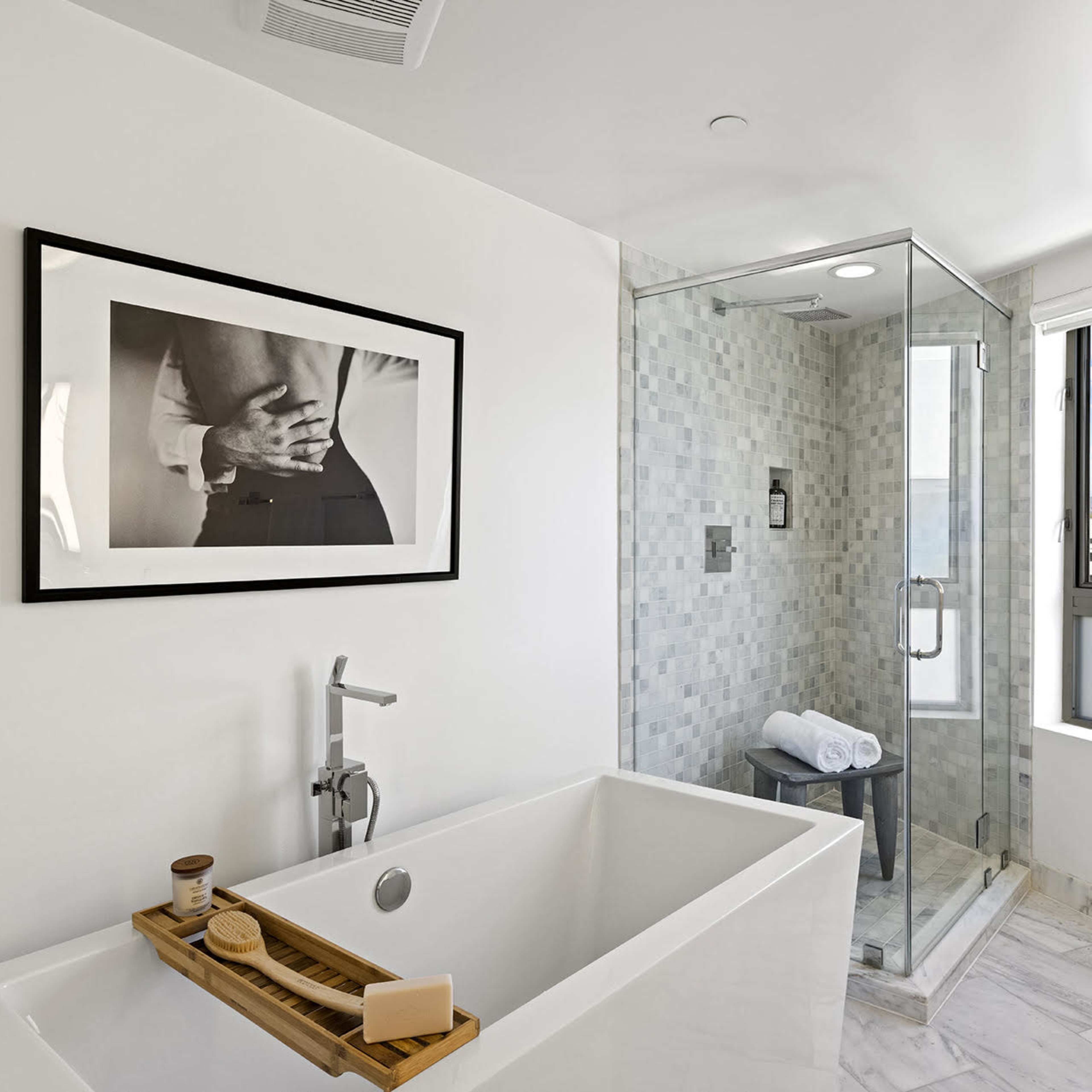 A modern bathroom featuring a freestanding bathtub and a glass shower enclosure with a tiled wall.