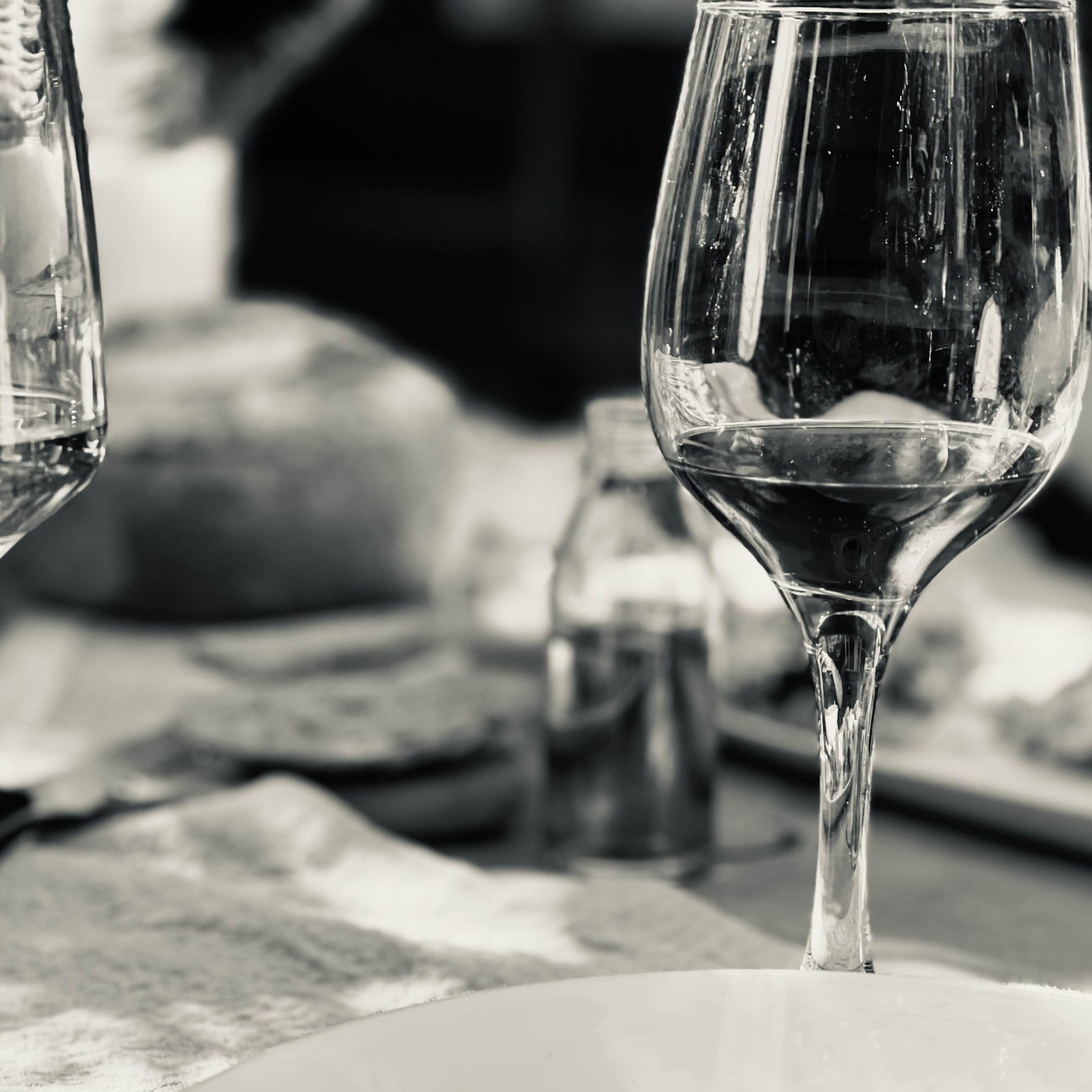 Two wine glasses filled with liquid are positioned on a table, surrounded by various dishes and utensils.