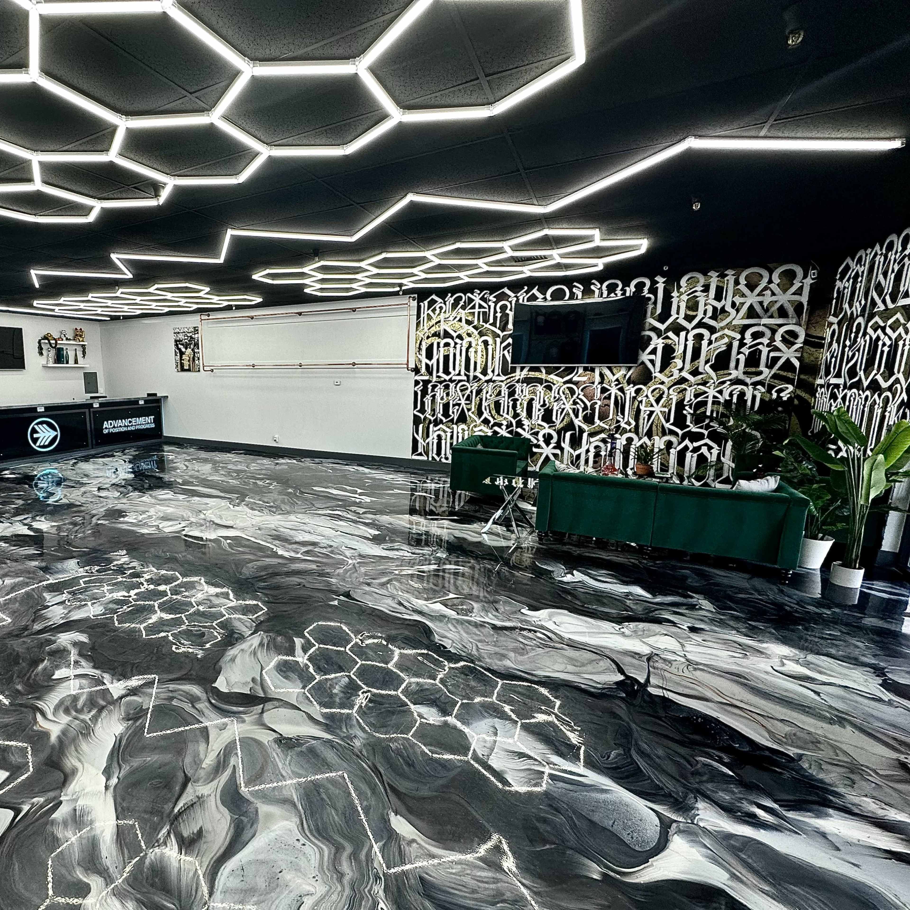A modern reception area with a black and white marbled floor, hexagonal ceiling lights, and a sleek front desk.