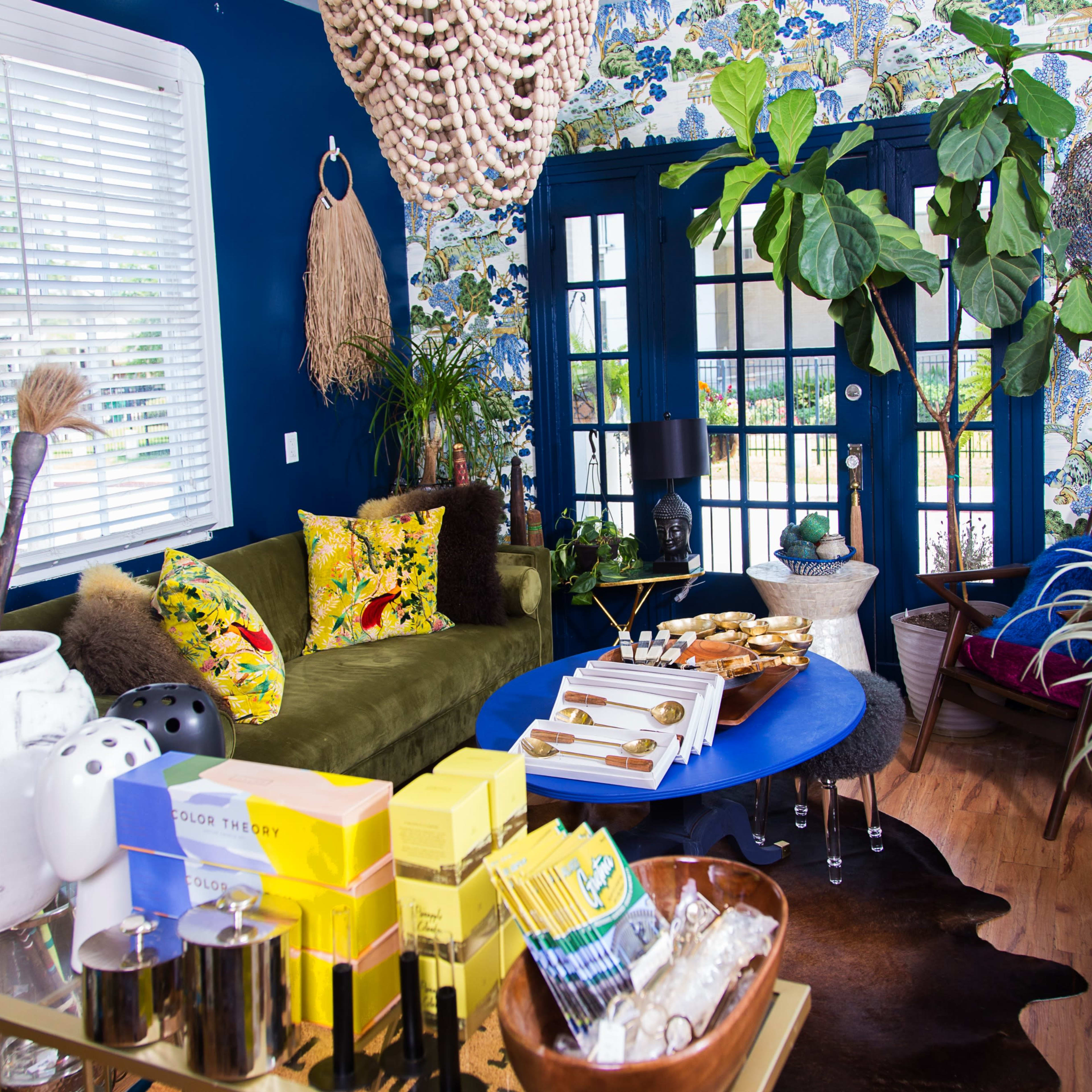 A vibrant living space featuring a mix of plants, decorative elements, and colorful furnishings against a bold wallpaper backdrop.