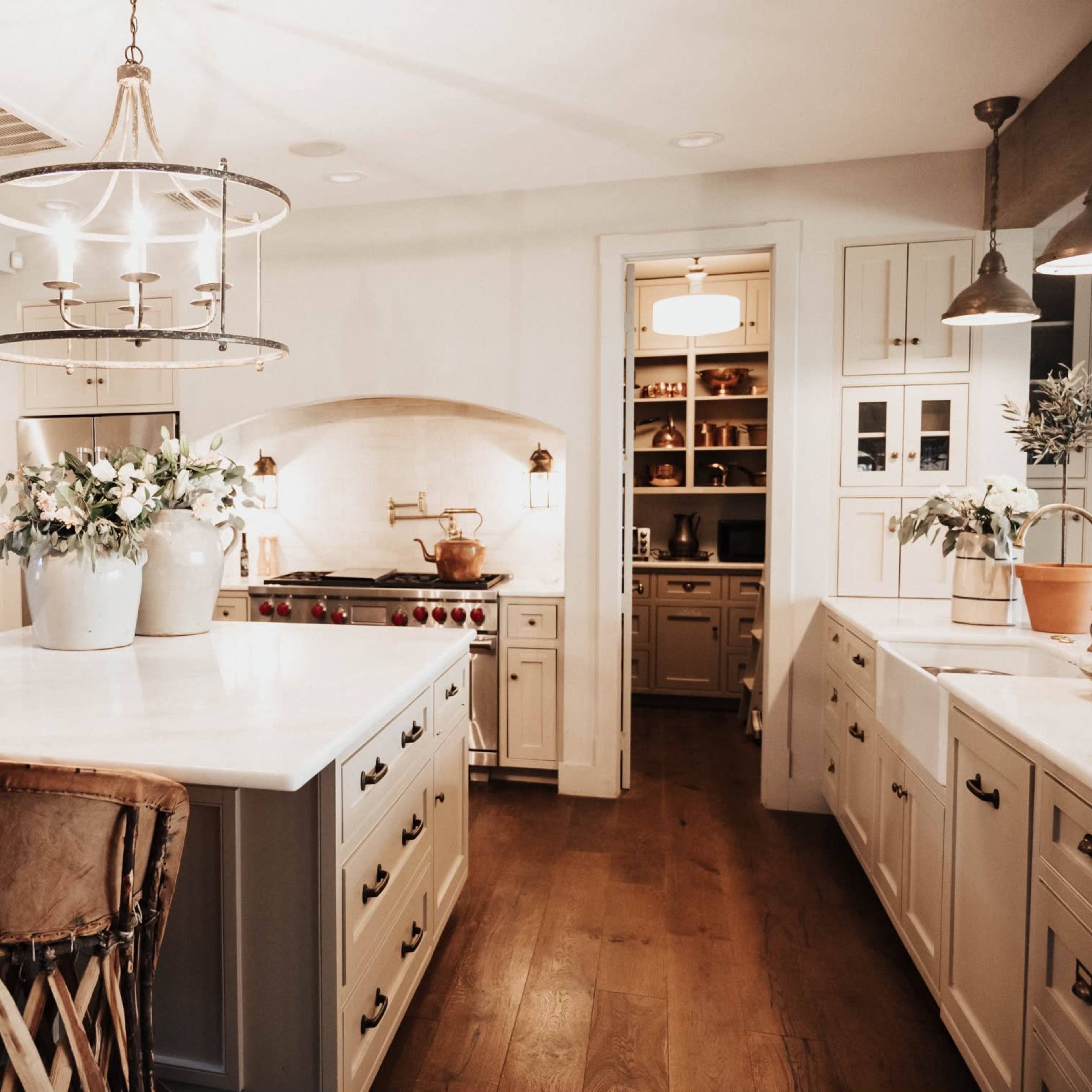 The kitchen features a central island with bar stools, white cabinetry, and a stove surrounded by a decorative arch.