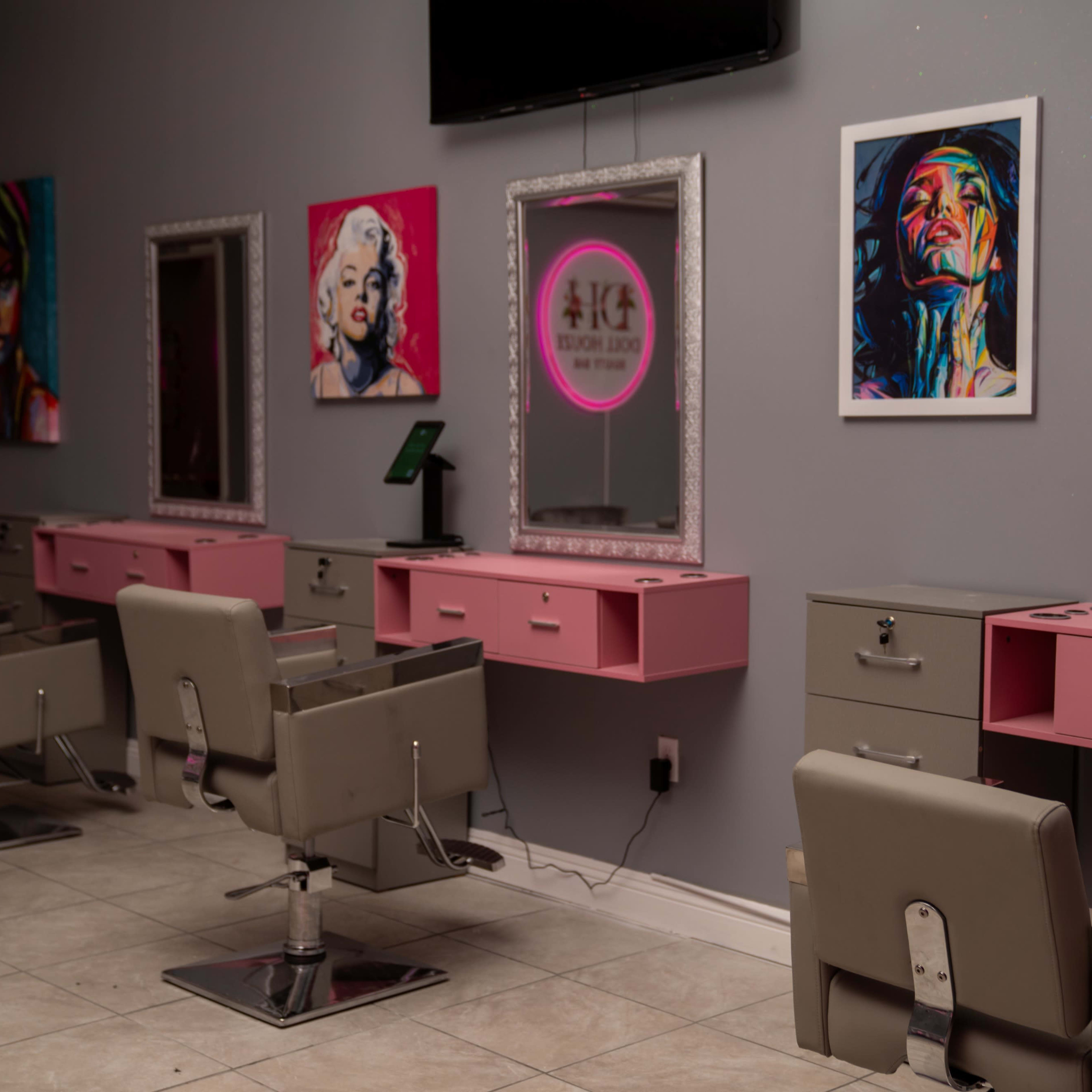 A modern salon interior with four styling stations, each equipped with a chair and a mirror, adorned with colorful artwork on the walls.