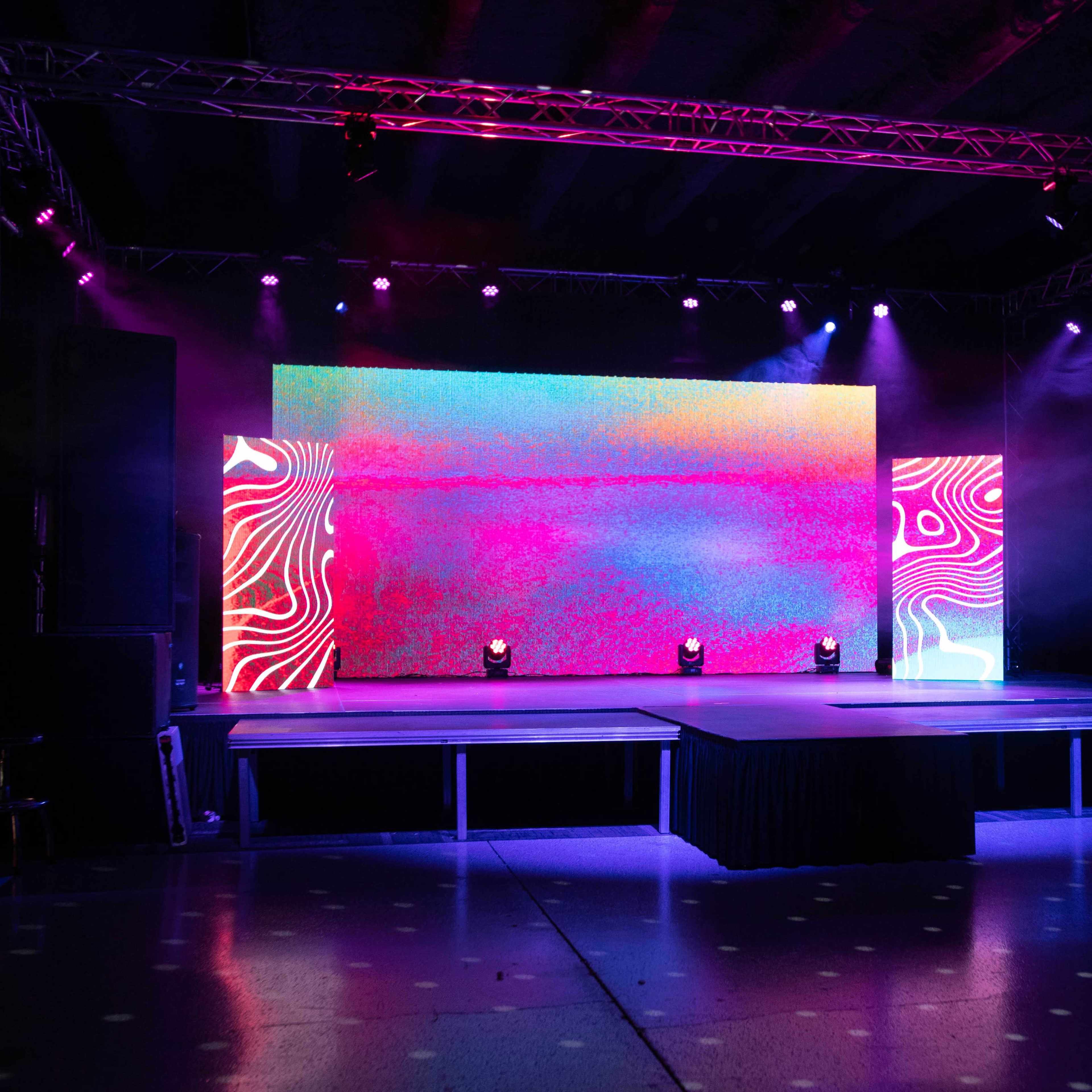 A stage is set up with colorful lighting and a large screen displaying vibrant patterns.