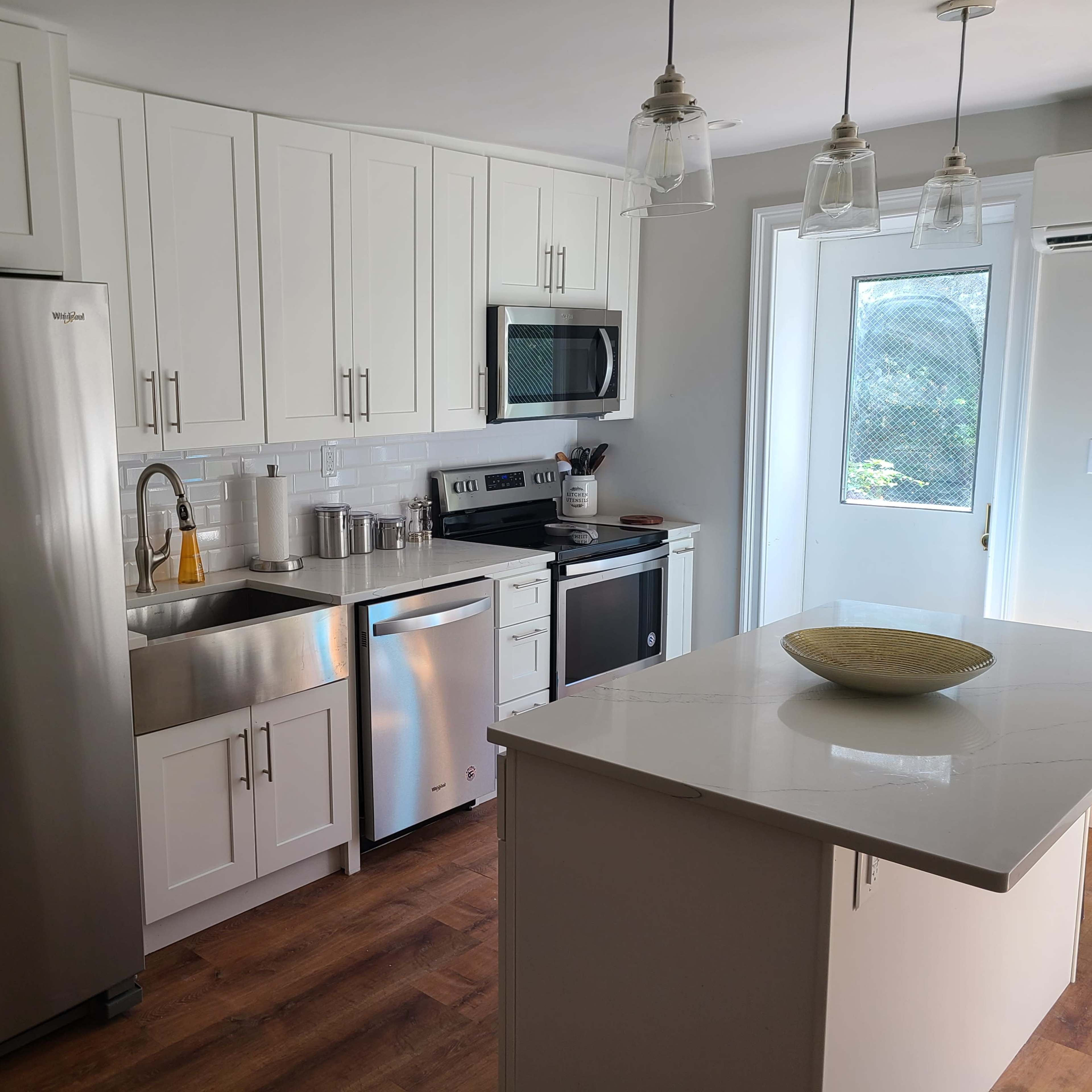 A modern kitchen with white cabinets, stainless steel appliances, and a central island featuring a decorative bowl.
