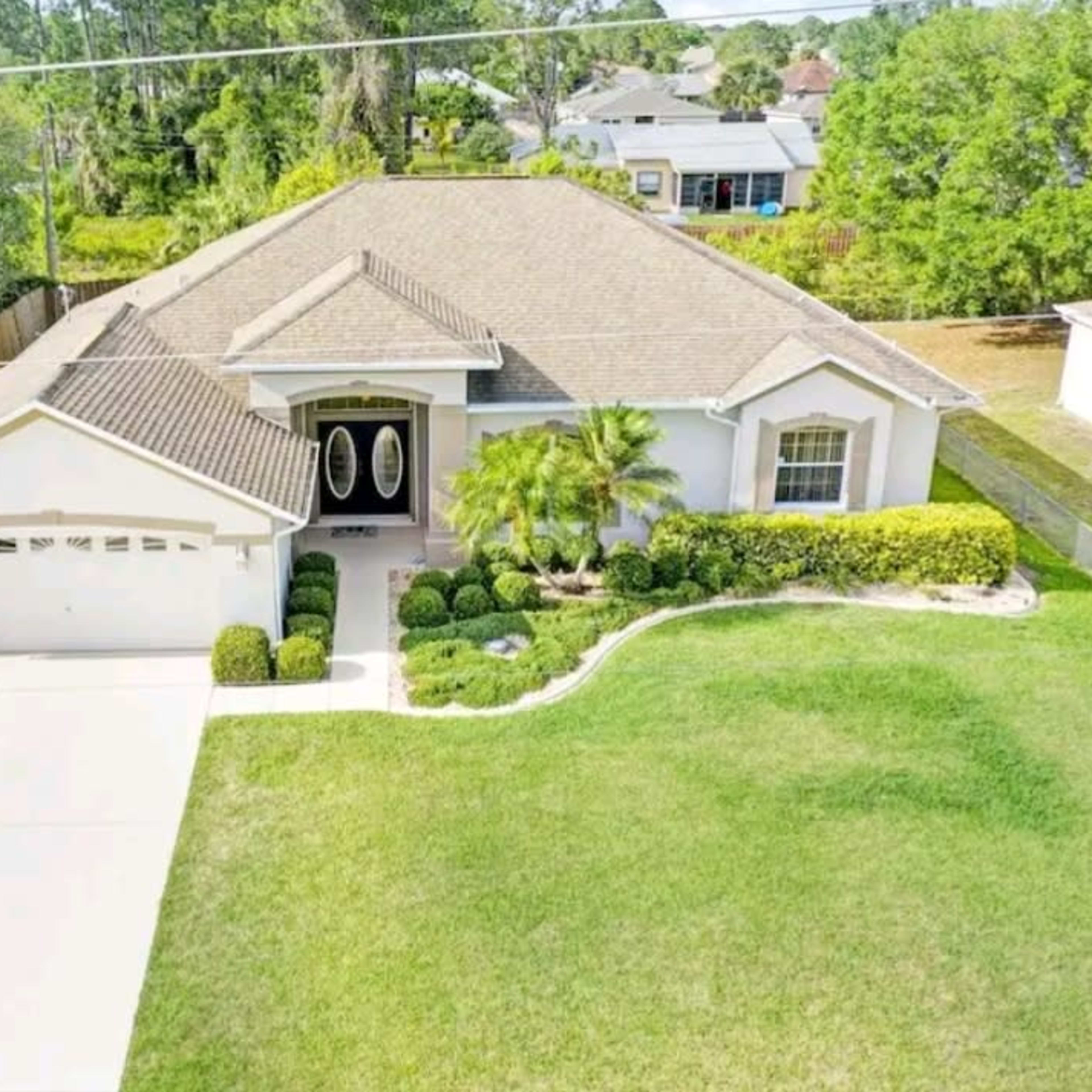 Aerial view of a single-story house with a manicured lawn and a driveway leading to a double garage.