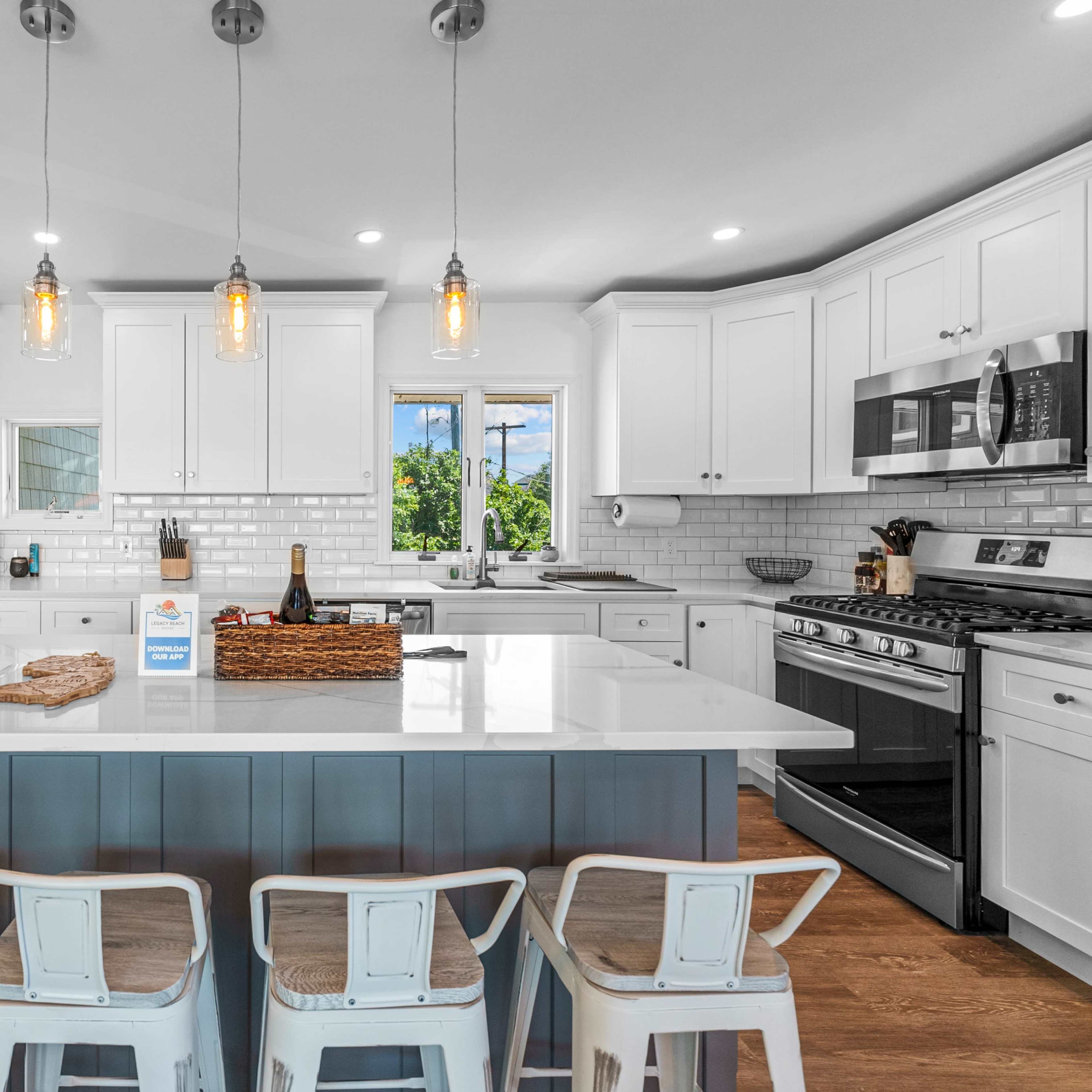 A modern kitchen features white cabinetry, a large island with bar seating, and windows that provide natural light.