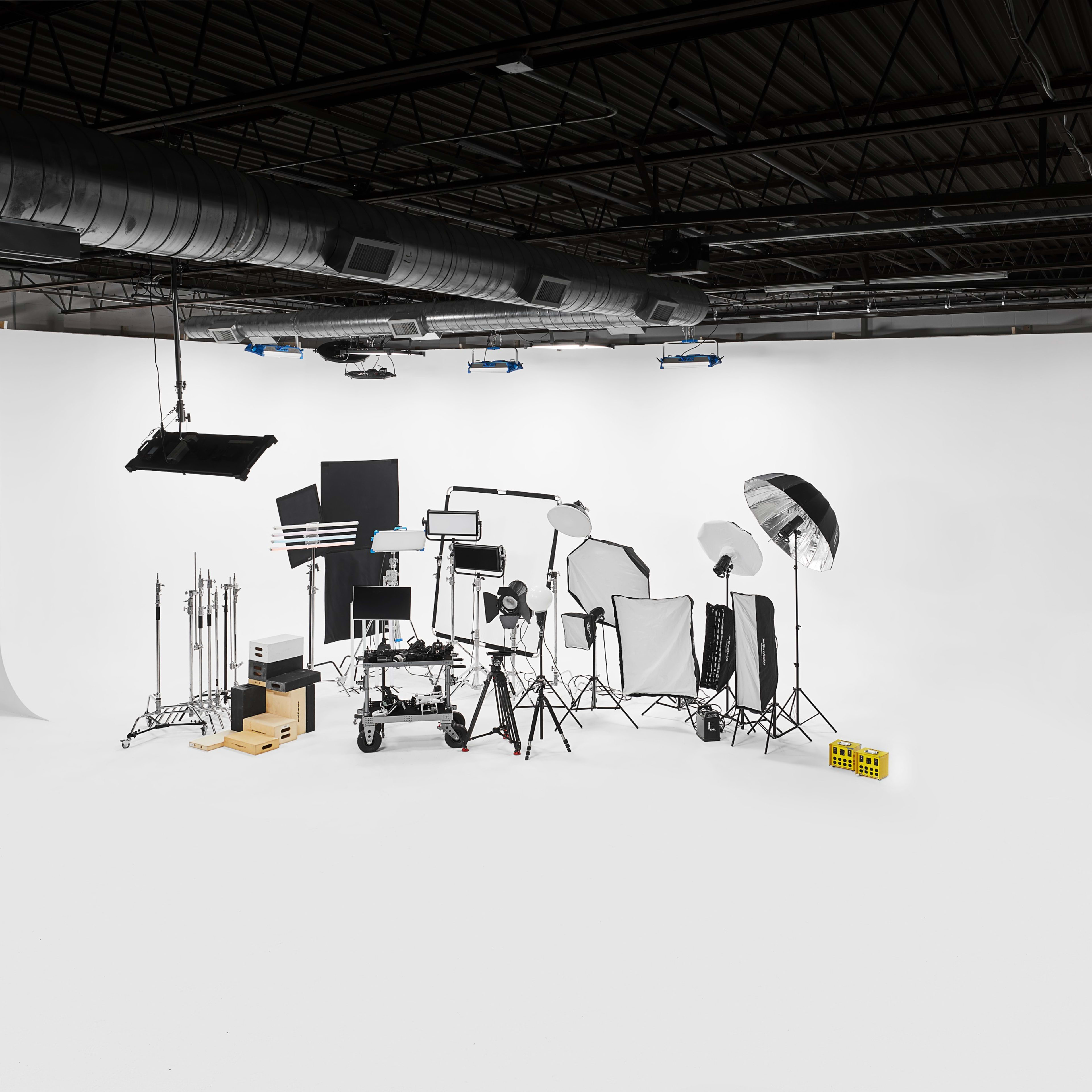 A photography studio equipped with various lighting and support equipment against a blank white backdrop.