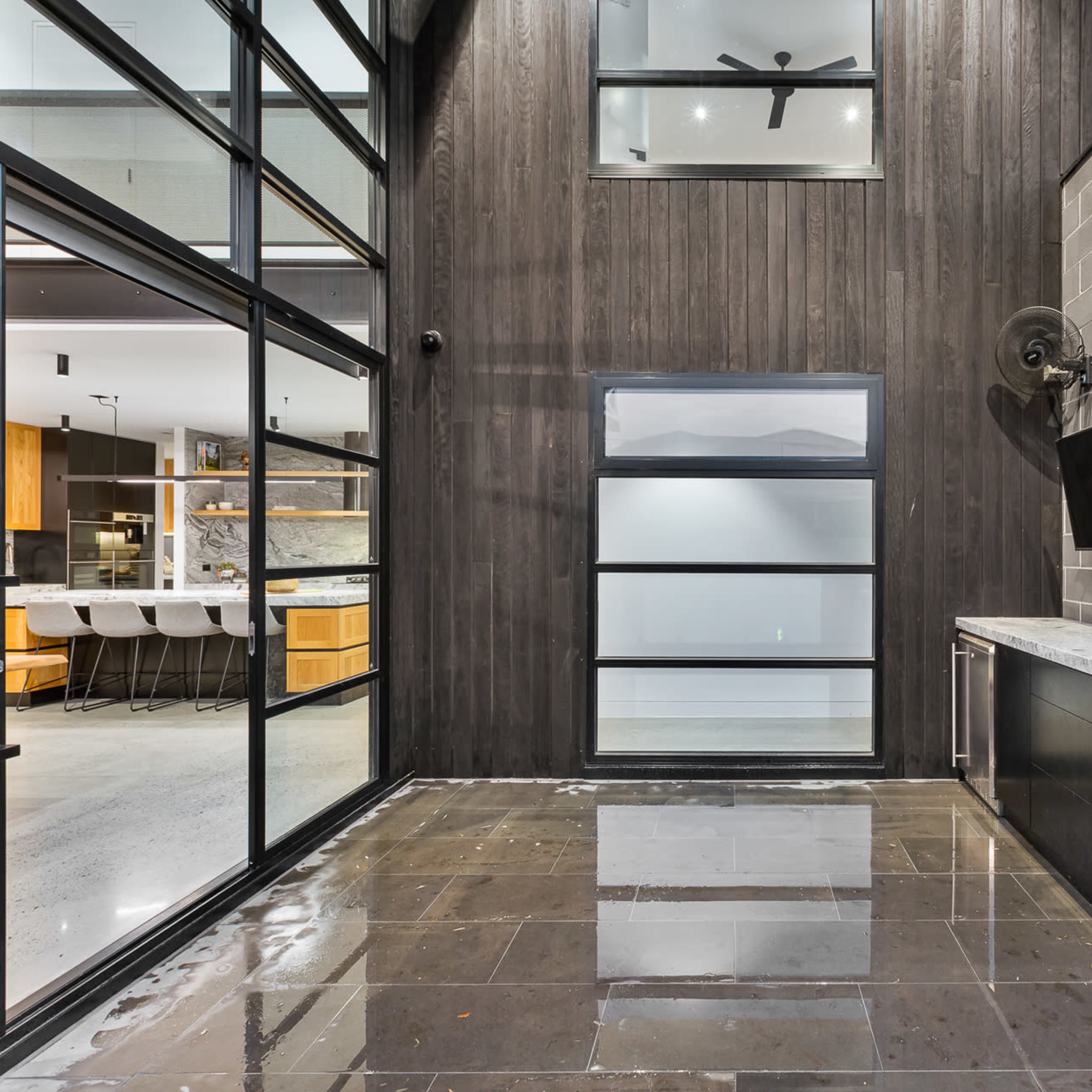 A modern outdoor patio with large glass doors, a stone countertop, and a wall made of gray bricks.