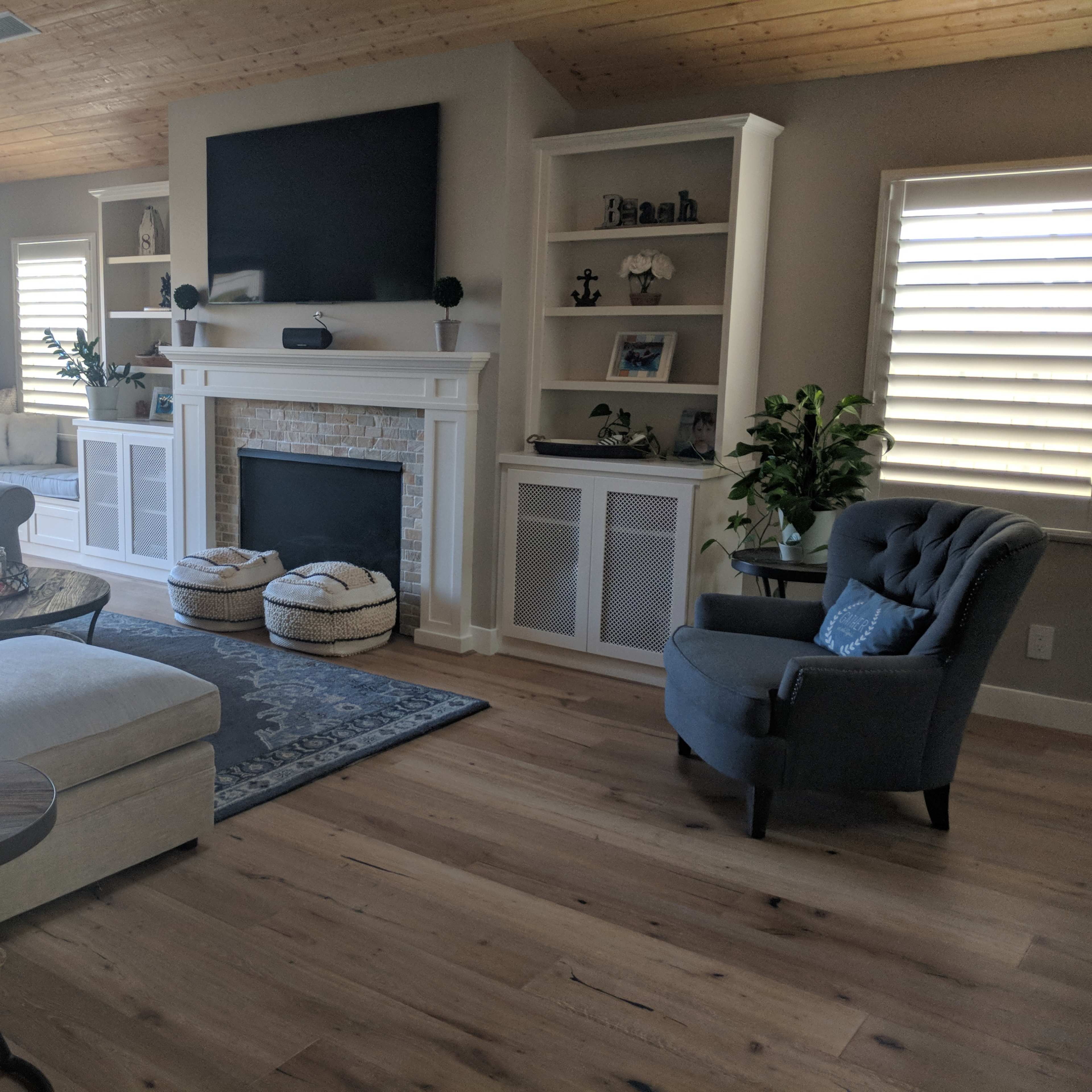 A modern living room featuring a sectional sofa, a coffee table, a large television above a fireplace, and built-in shelves filled with decorative items.