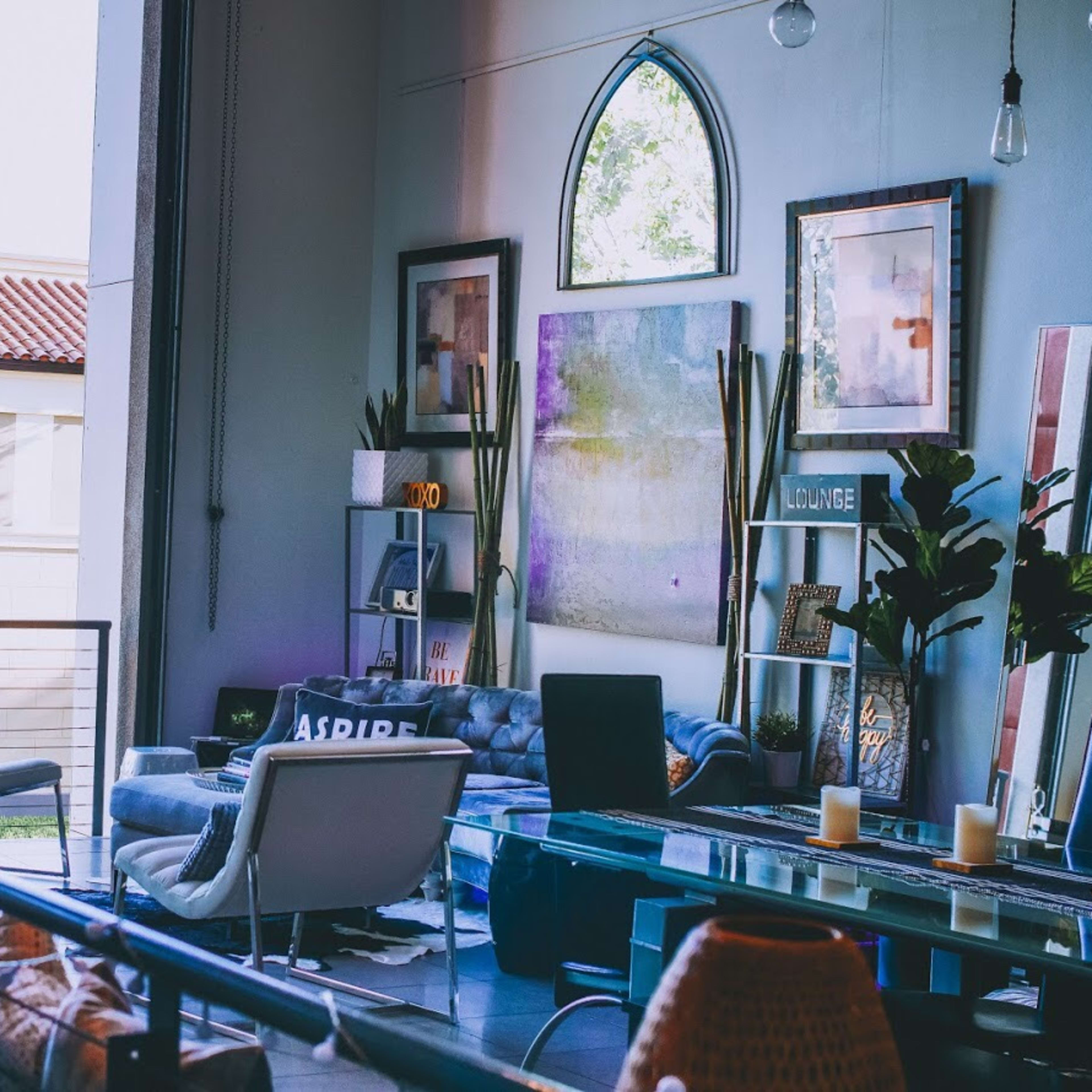 A modern living room with large windows, contemporary furniture, and decorative plants.