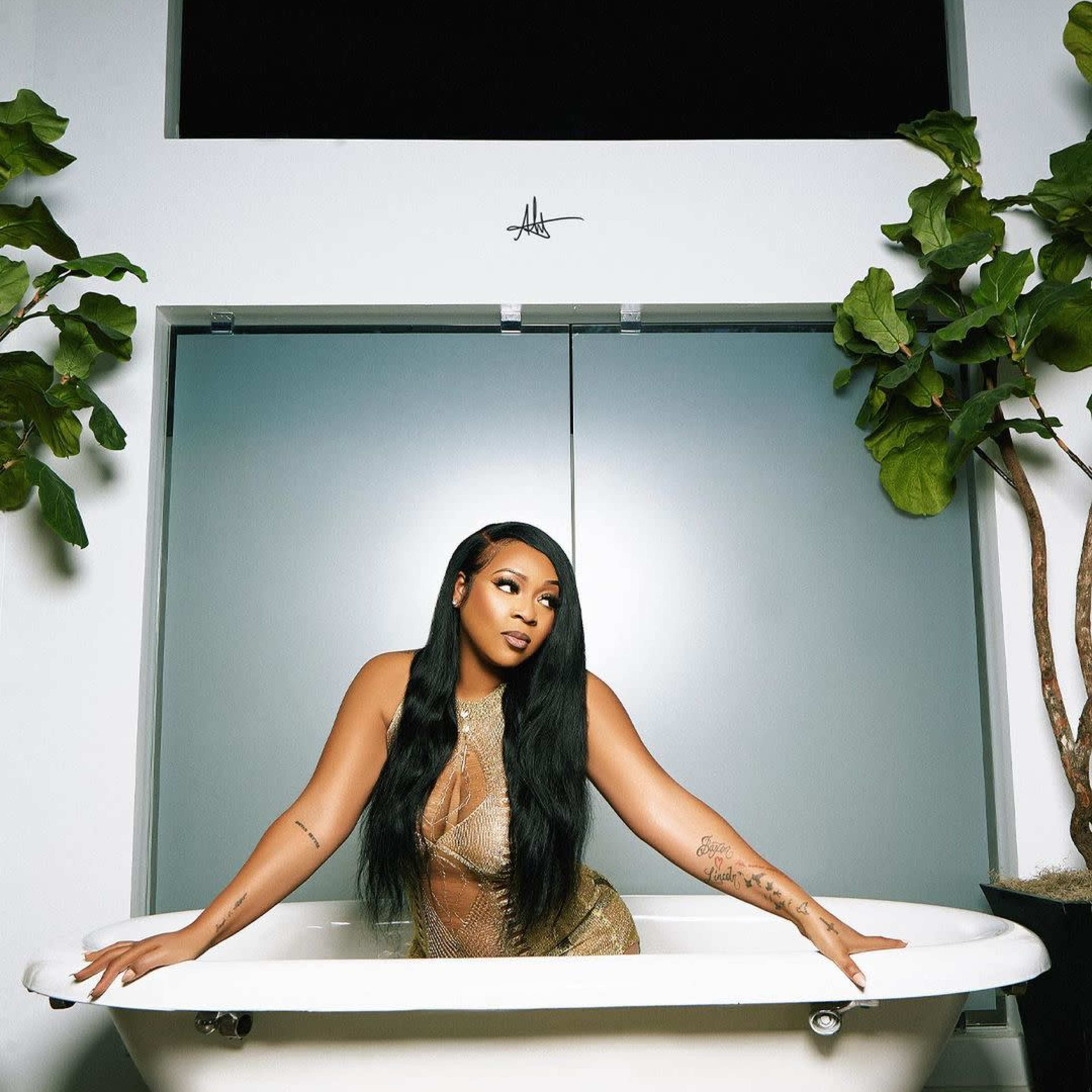 A woman poses in a white bathtub surrounded by indoor plants and modern decor.
