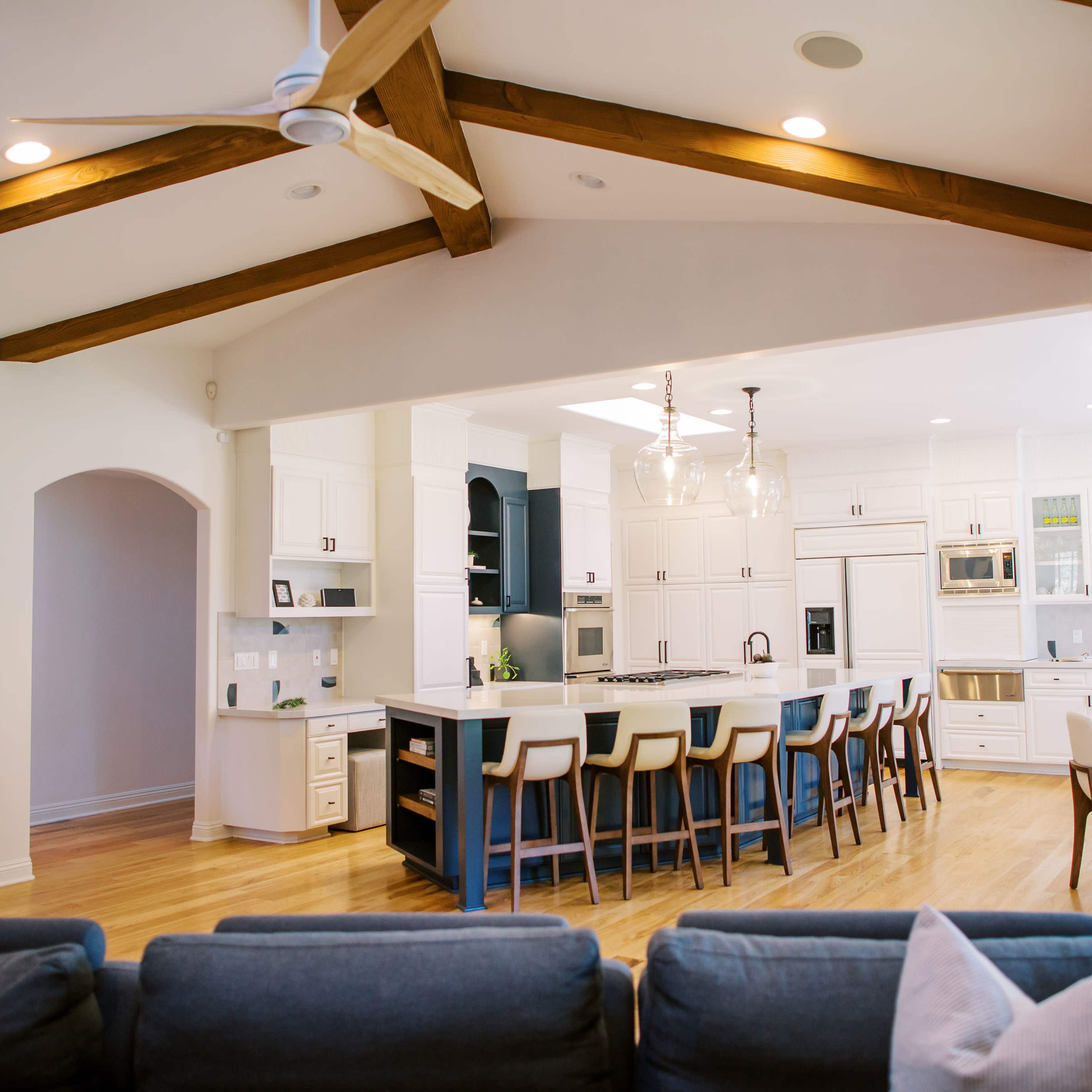 A spacious kitchen with an island, bar stools, and wooden beams across the ceiling.