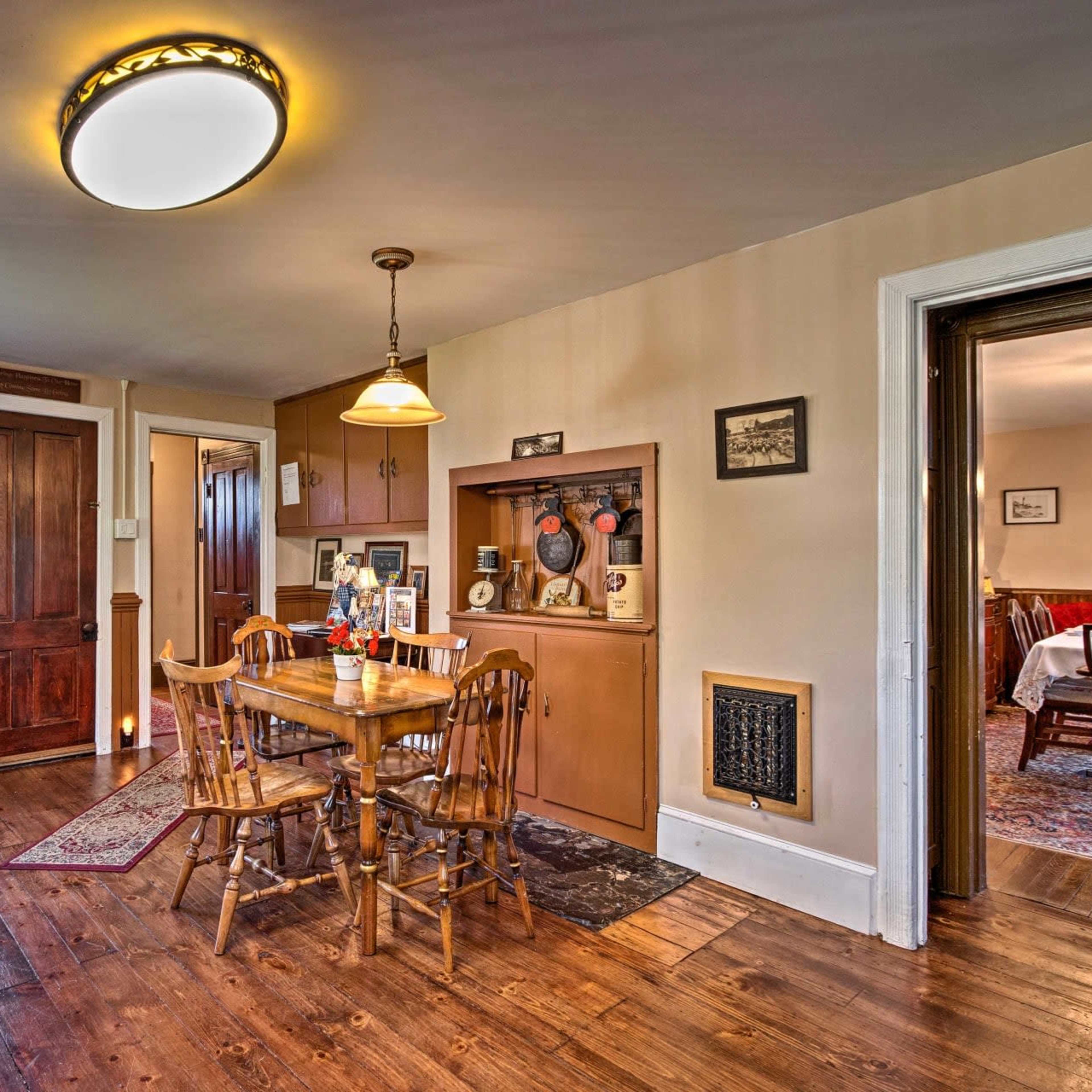 A cozy dining area with a wooden table and chairs, surrounded by warm-toned walls and a door leading to another room.