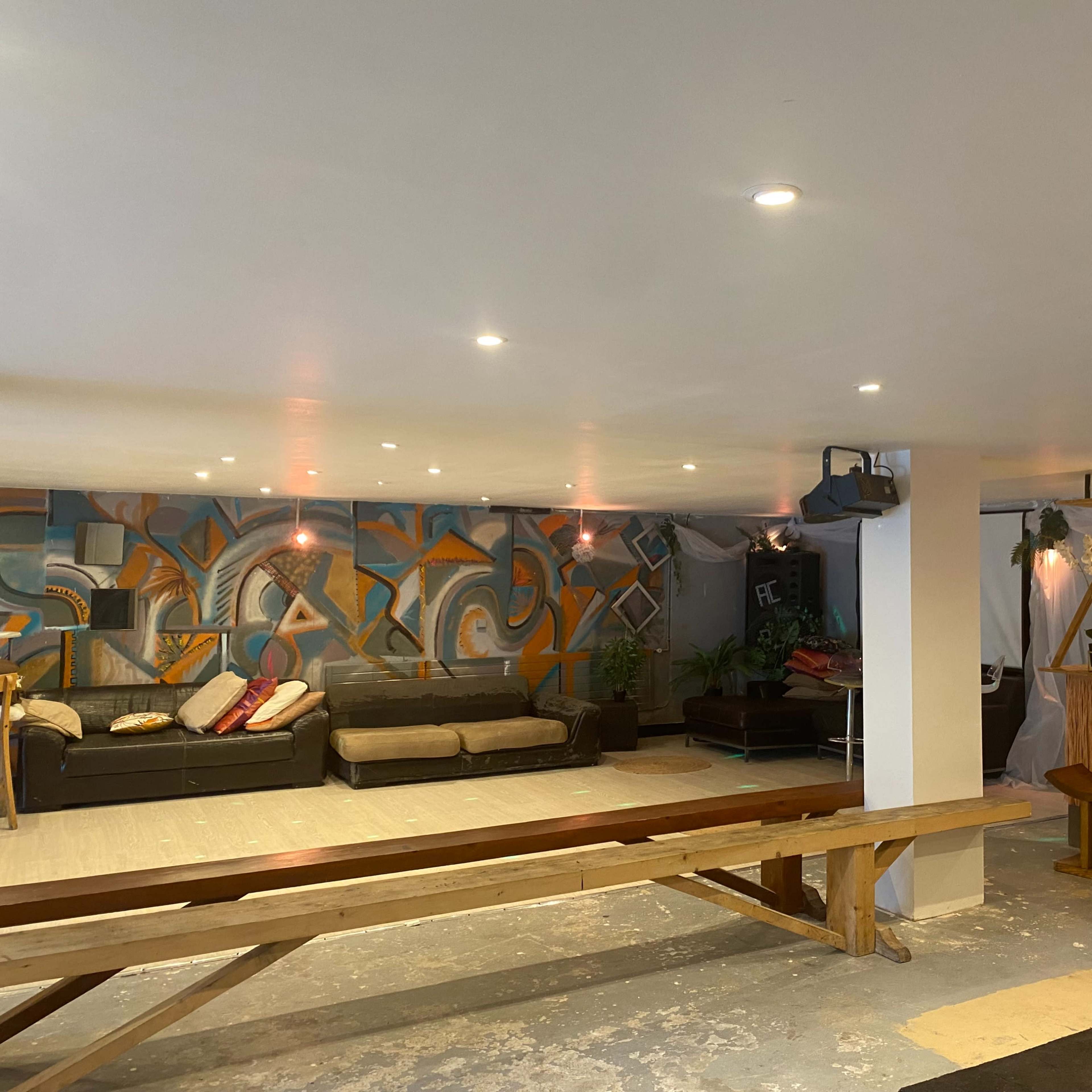 A spacious indoor area with a bar, seating arrangements, and colorful wall murals.