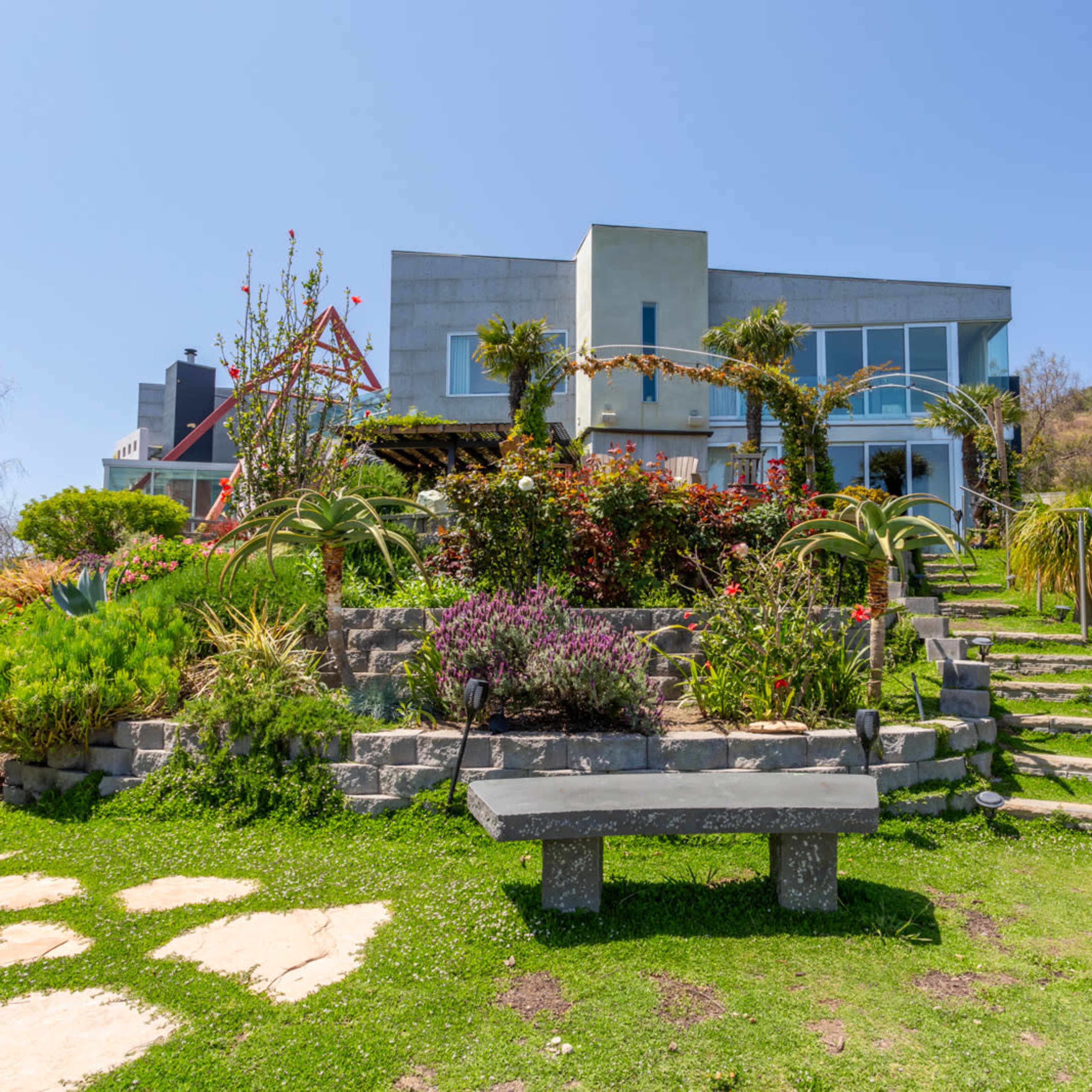 A modern house surrounded by a landscaped garden with steps leading up to the entrance.