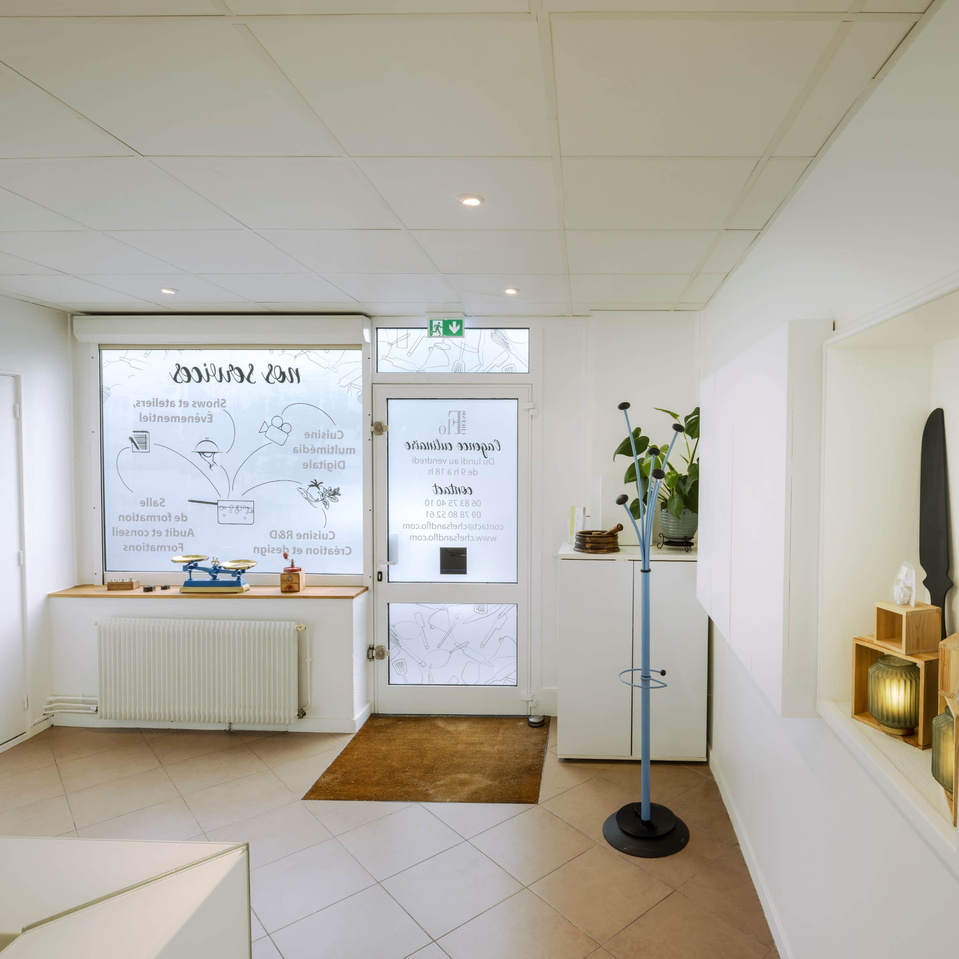 A bright, modern reception area featuring a large window, decorative plants, and minimalist furnishings.