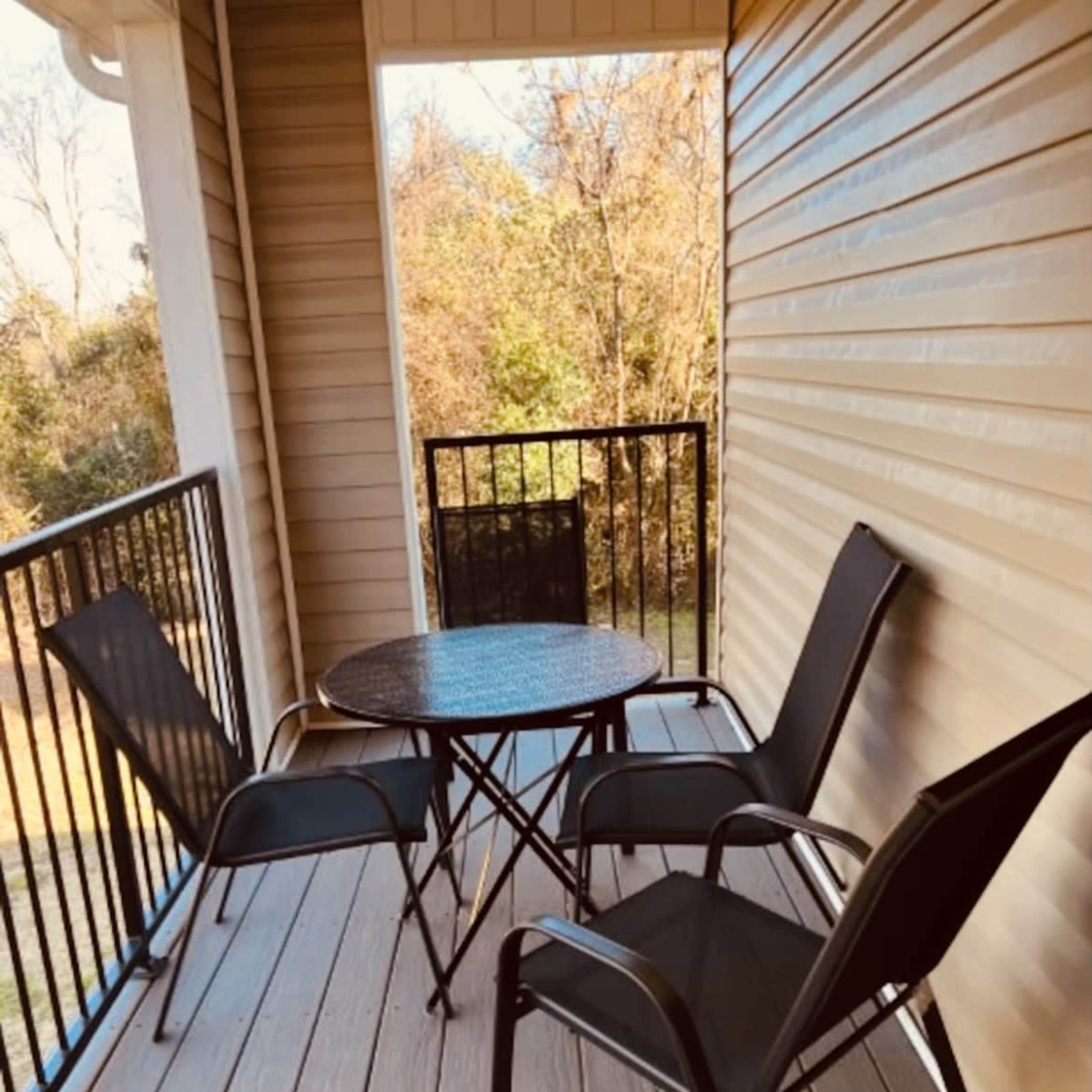 A small balcony features a round table and four folding chairs.
