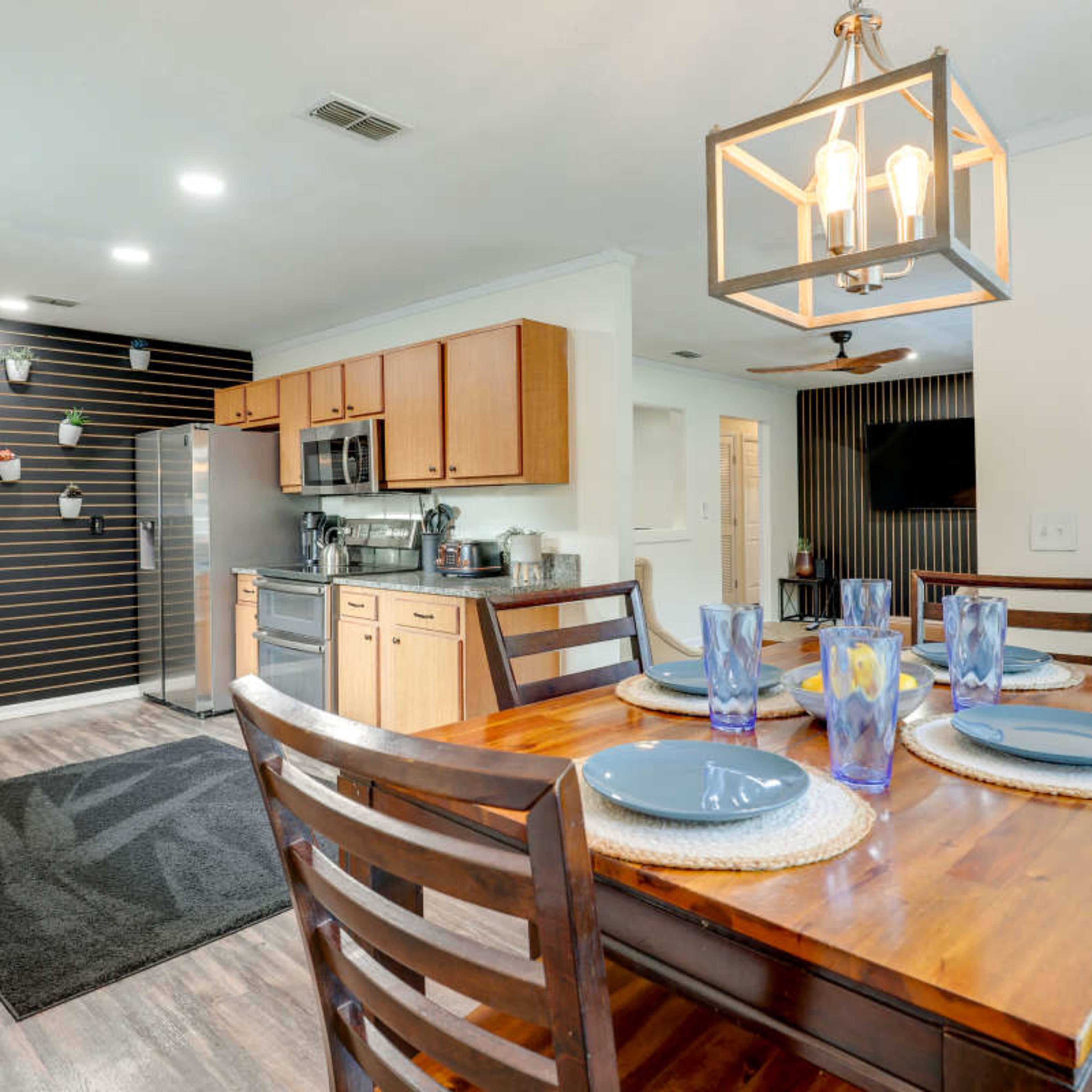 A kitchen with wooden cabinets, a dining table set for four, and stainless steel appliances.