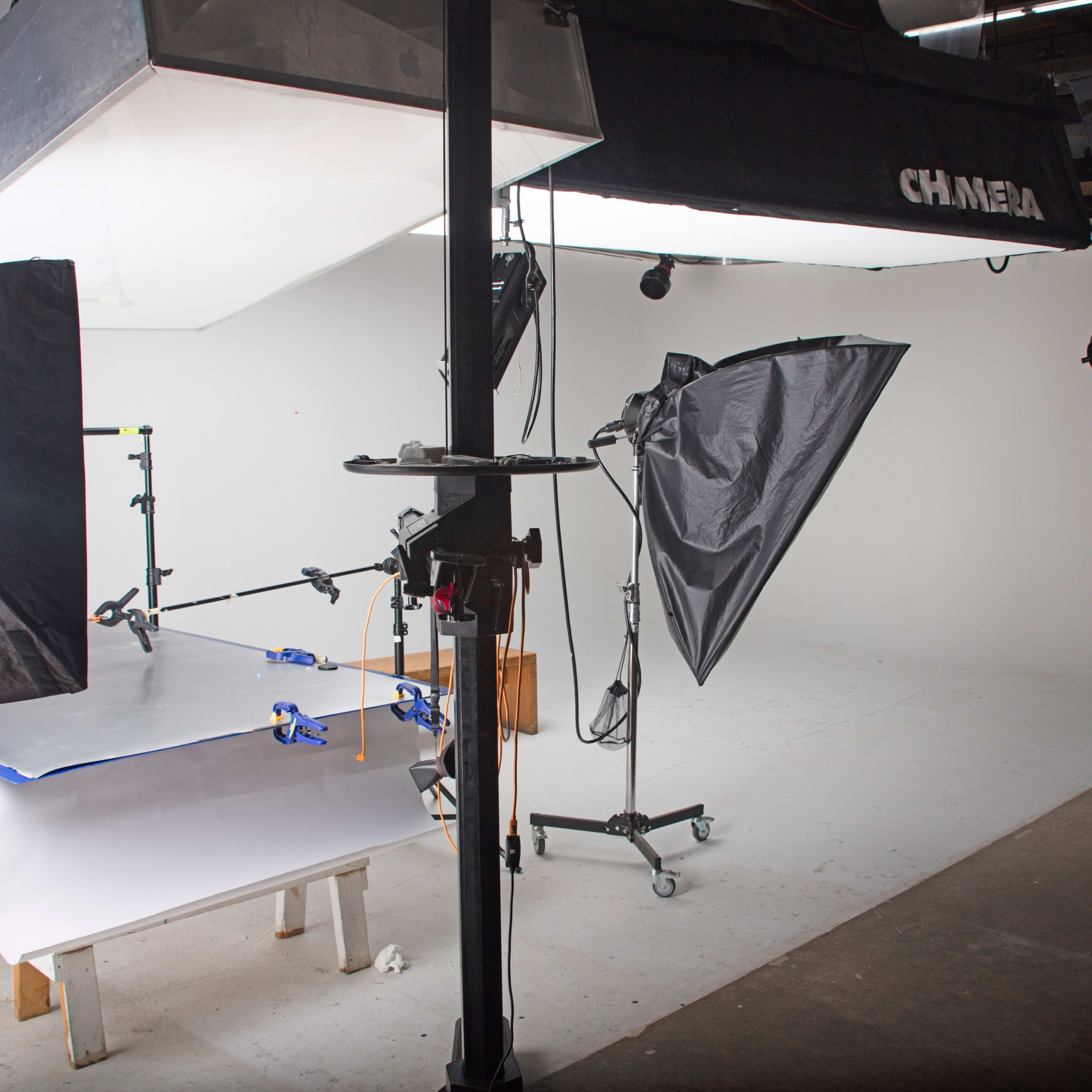 A photography studio equipped with softboxes, a backdrop, and a table set up for a shoot.
