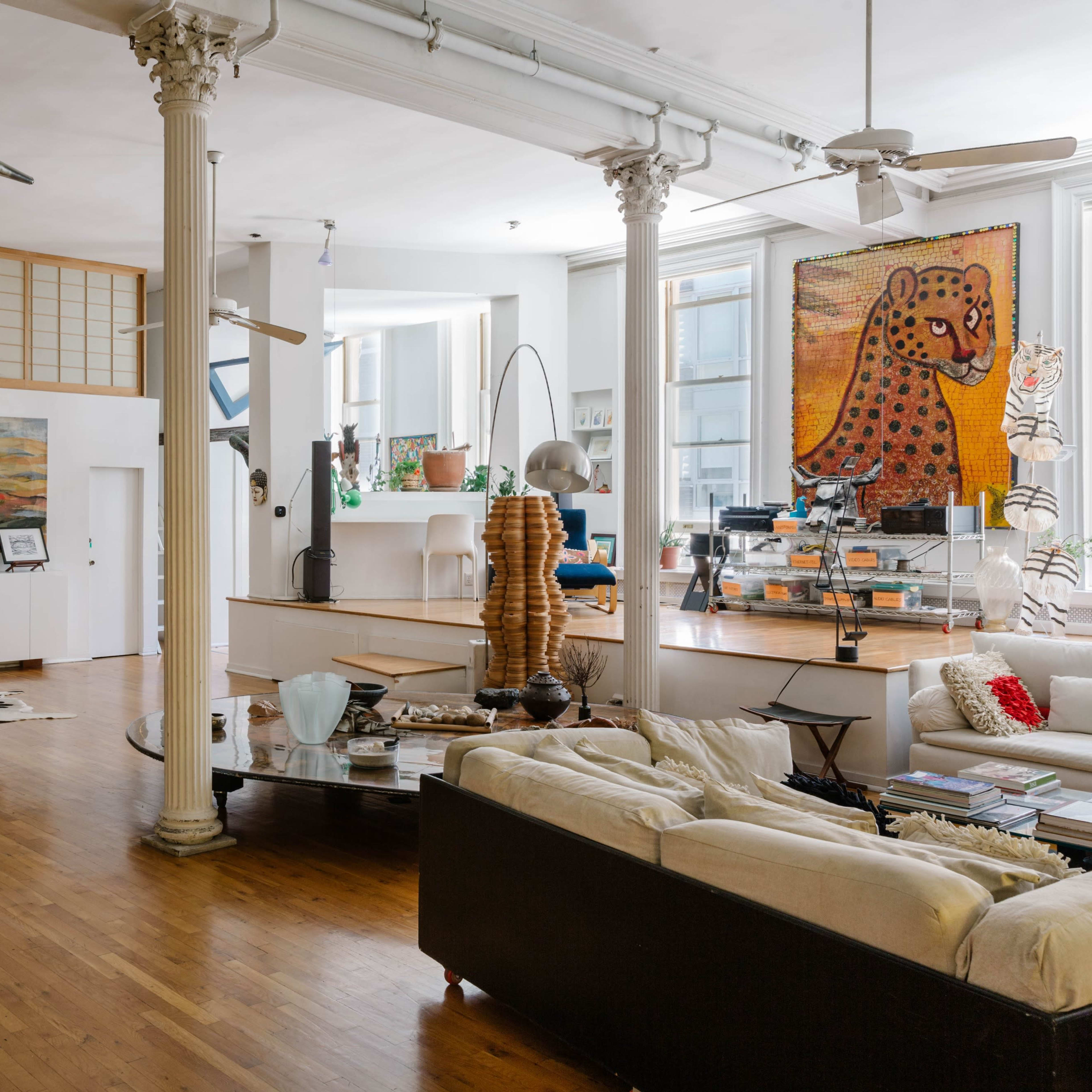 A spacious, well-lit loft featuring a piano, modern furniture, and large artworks on the walls.