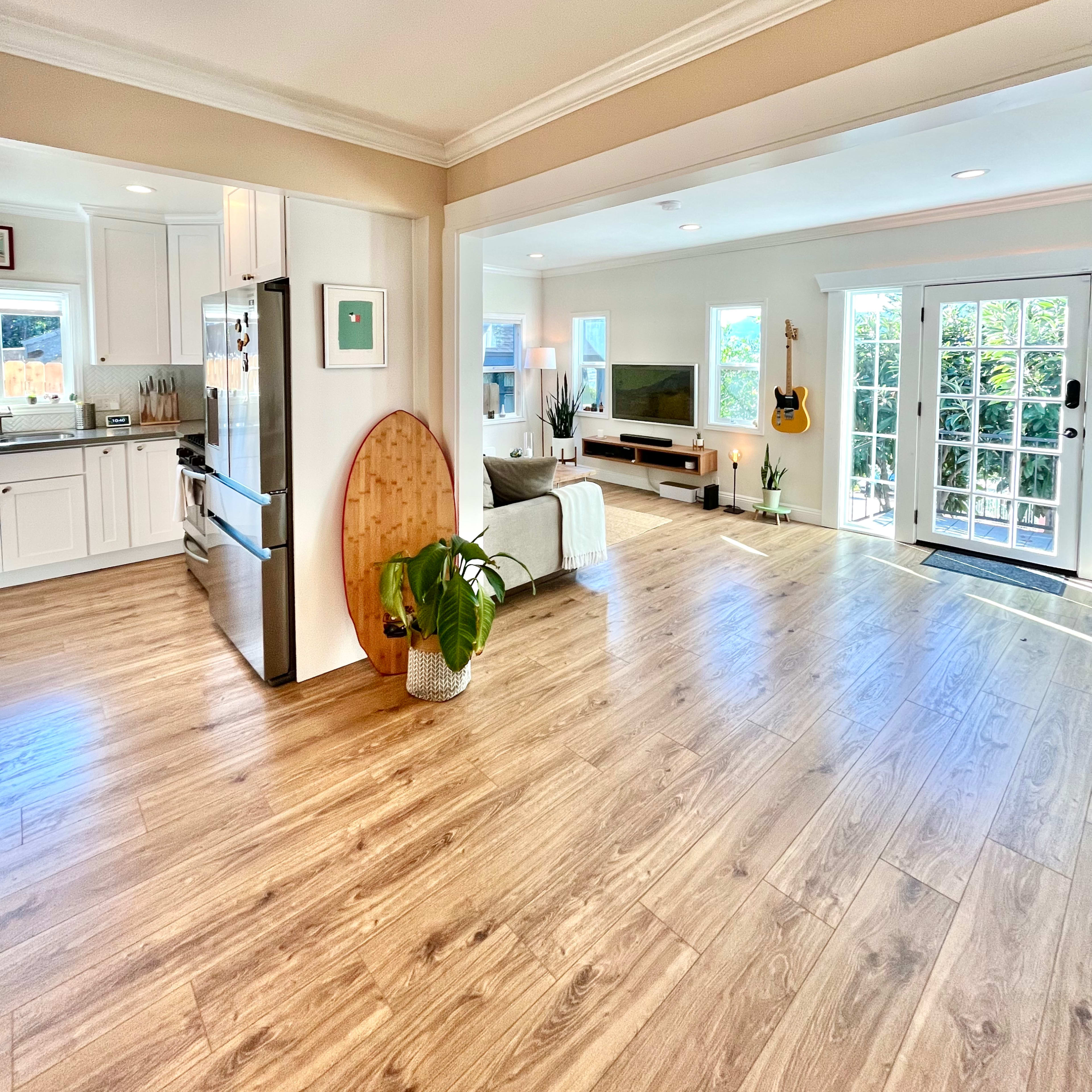 A spacious living area features a kitchen on the left, a seating area with a television on the right, and large glass doors leading outside.