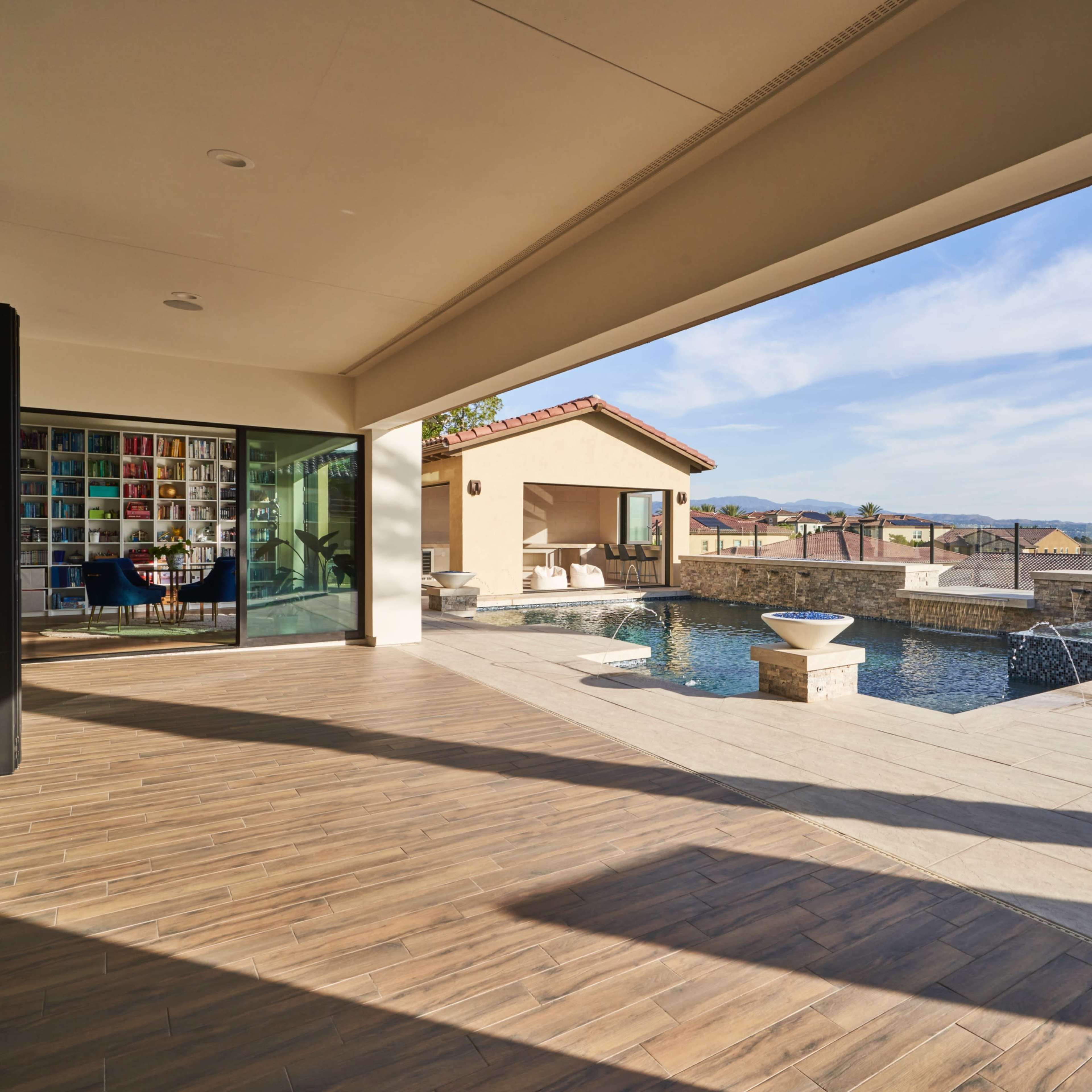 A modern patio area overlooking a swimming pool with a scenic view and landscaped surroundings.