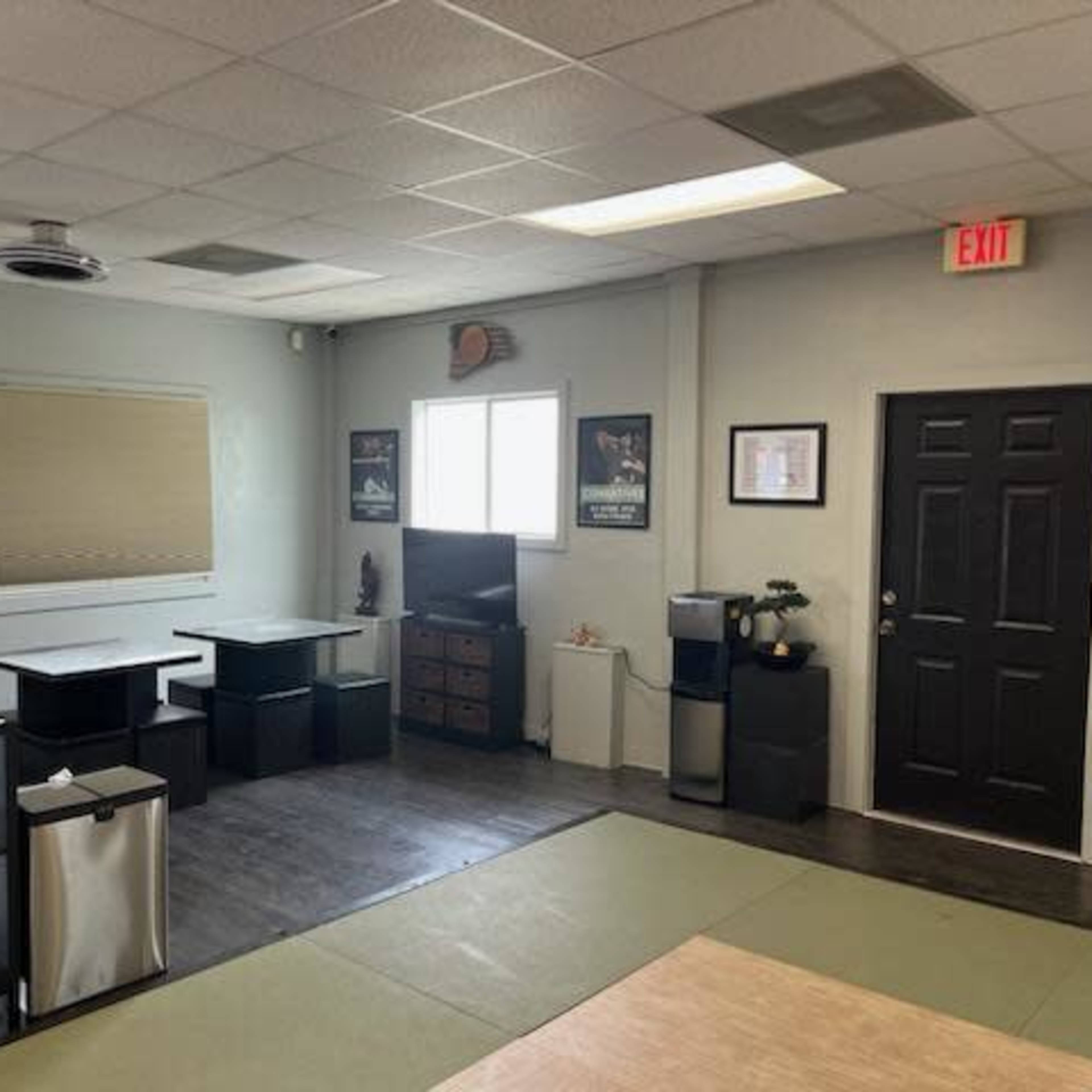 A bright office space with several desks, a television, and a door leading to an exit.