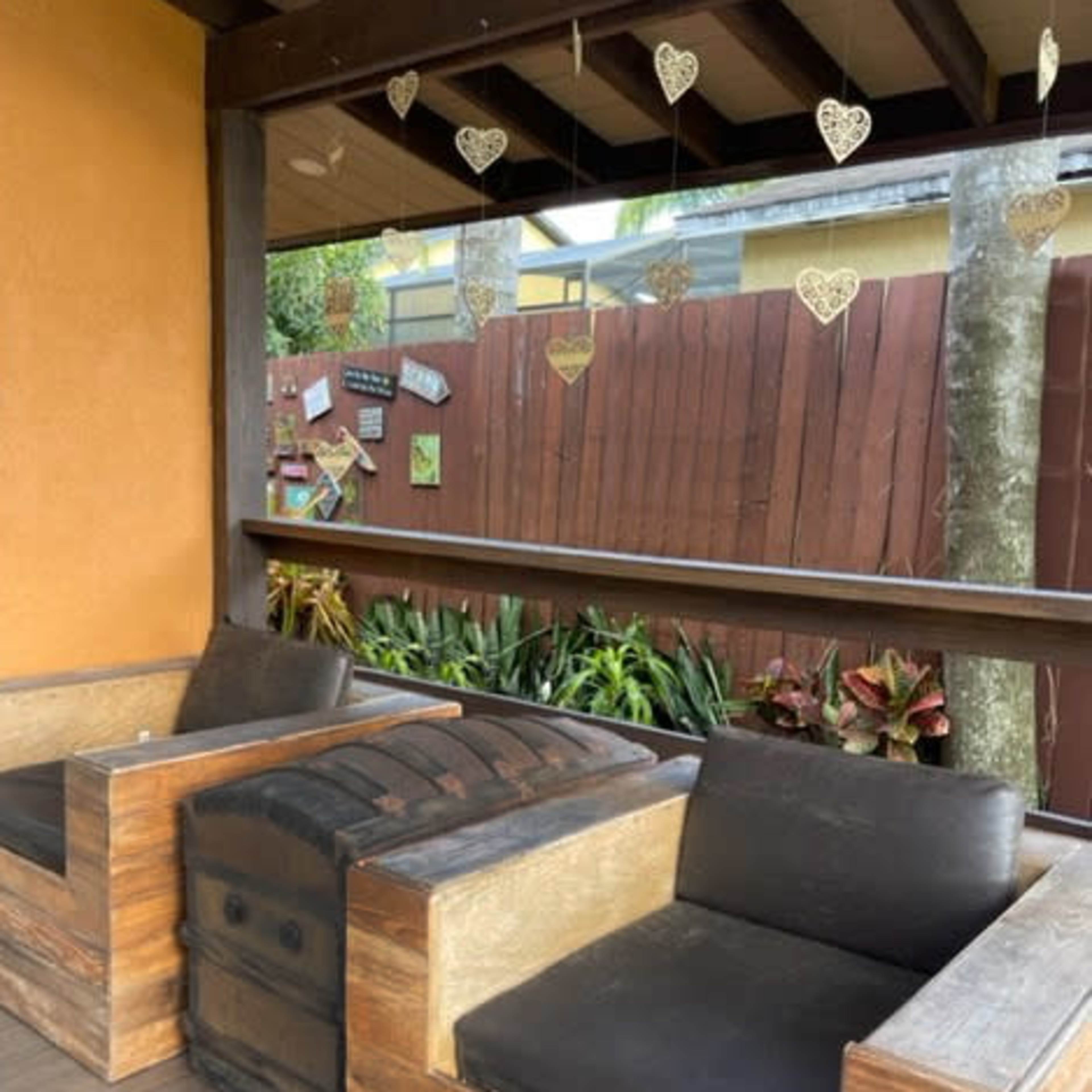 A wooden seating area with two couches on a porch, surrounded by a wooden fence and hanging heart decorations.