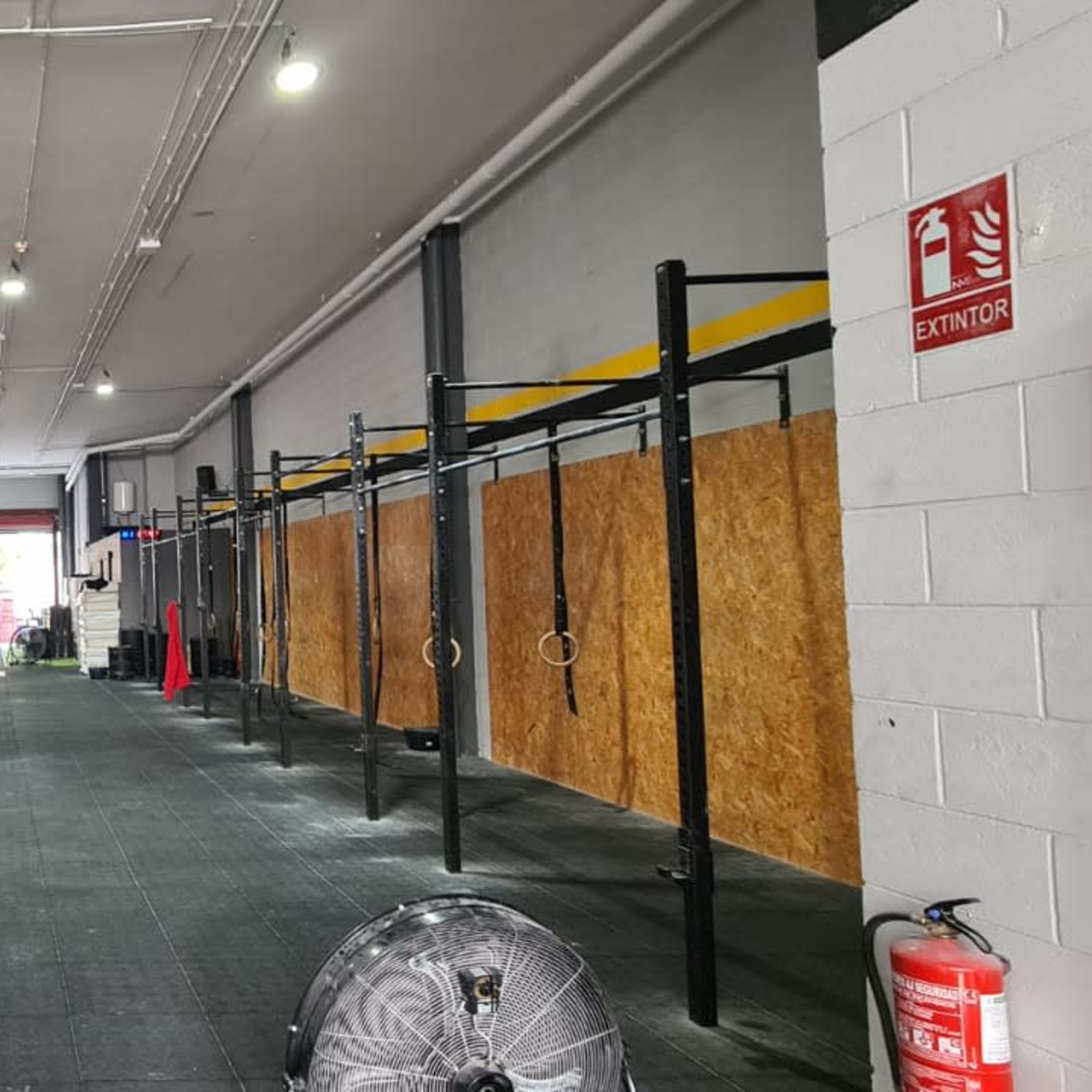 A spacious gym area with wooden box platforms on one side and a series of pull-up bars along the wall.