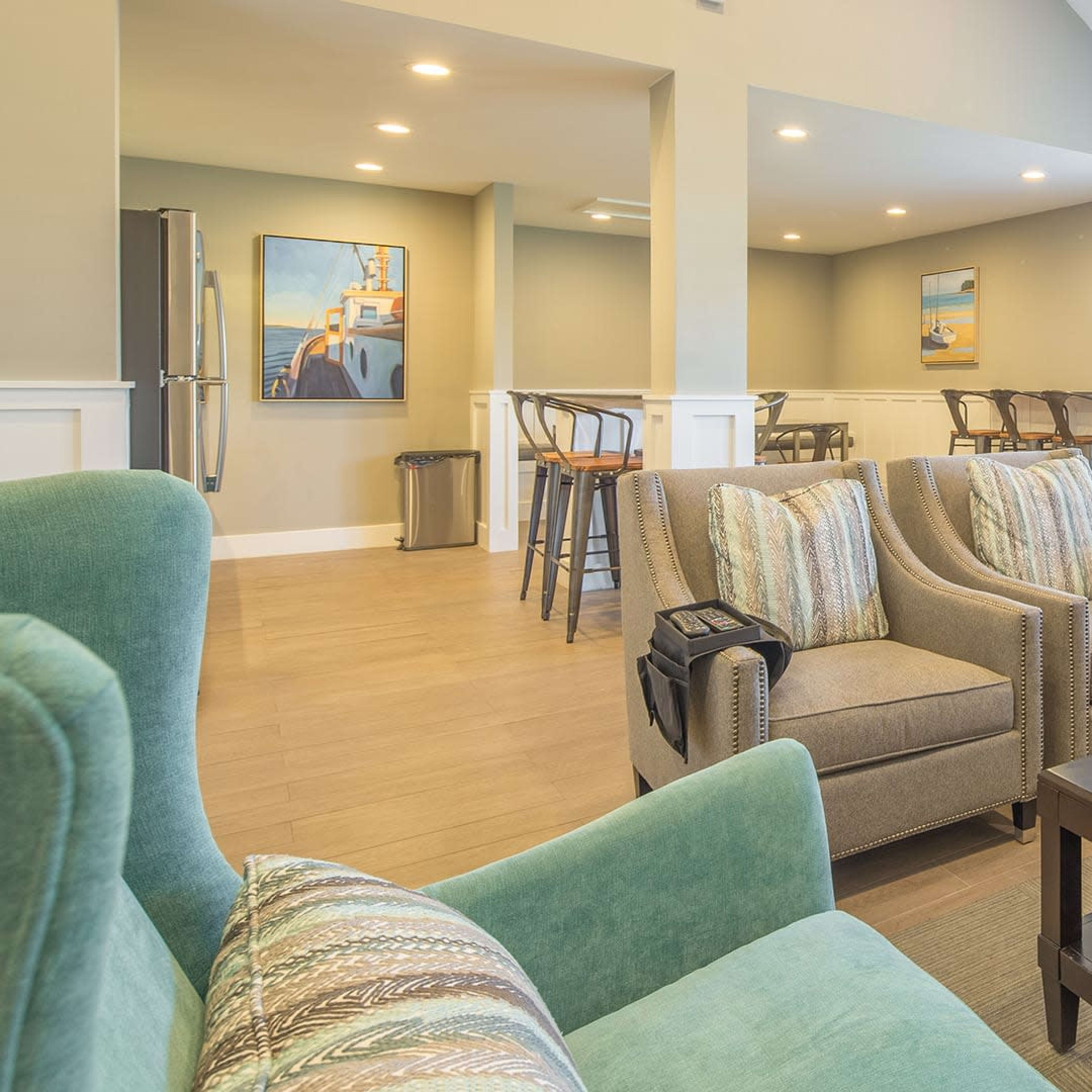 A cozy lounge area with gray sofas, a dark coffee table, and a bar-style seating arrangement in the background.