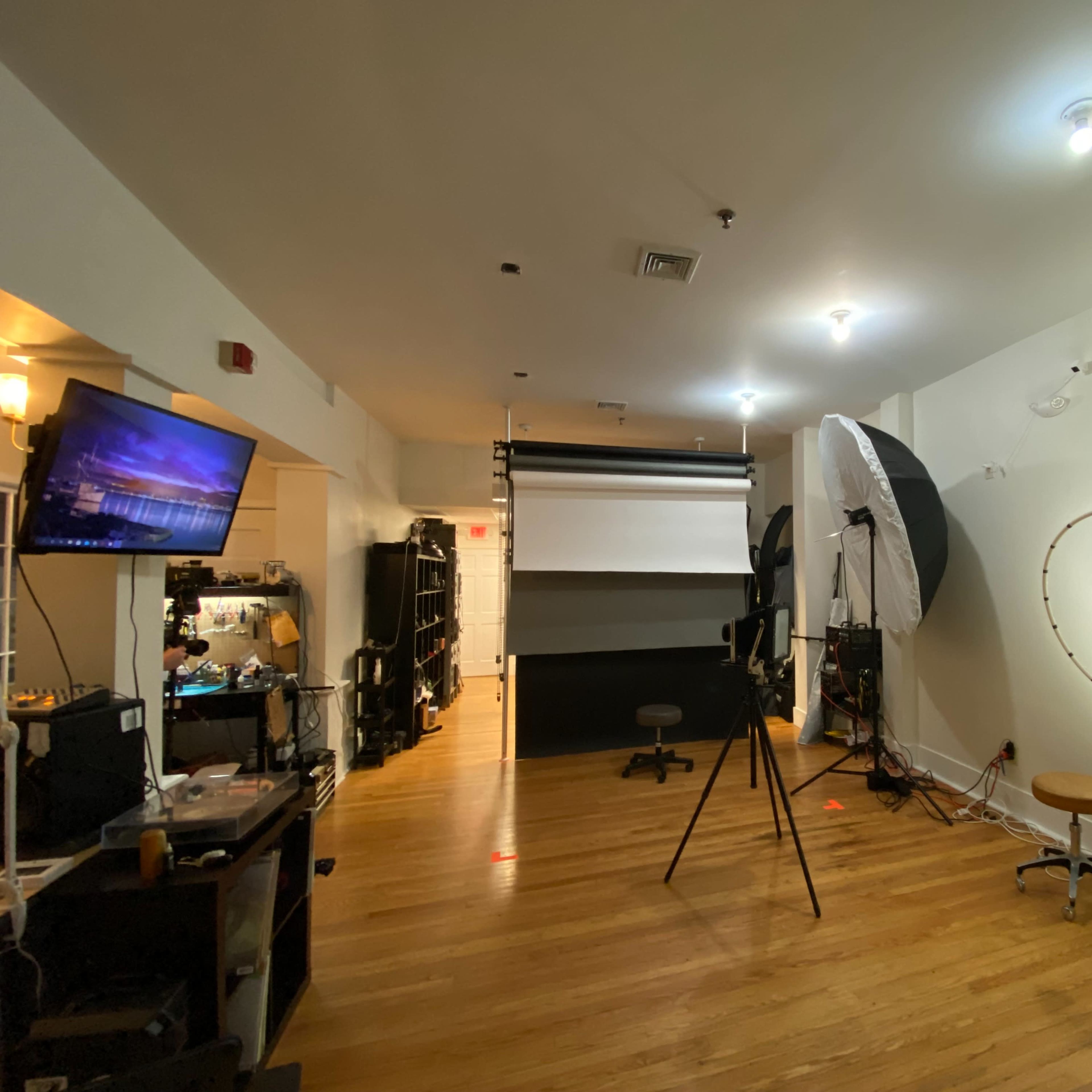 A photography studio featuring multiple lighting setups, a backdrop, and a variety of equipment arranged in a well-lit room.