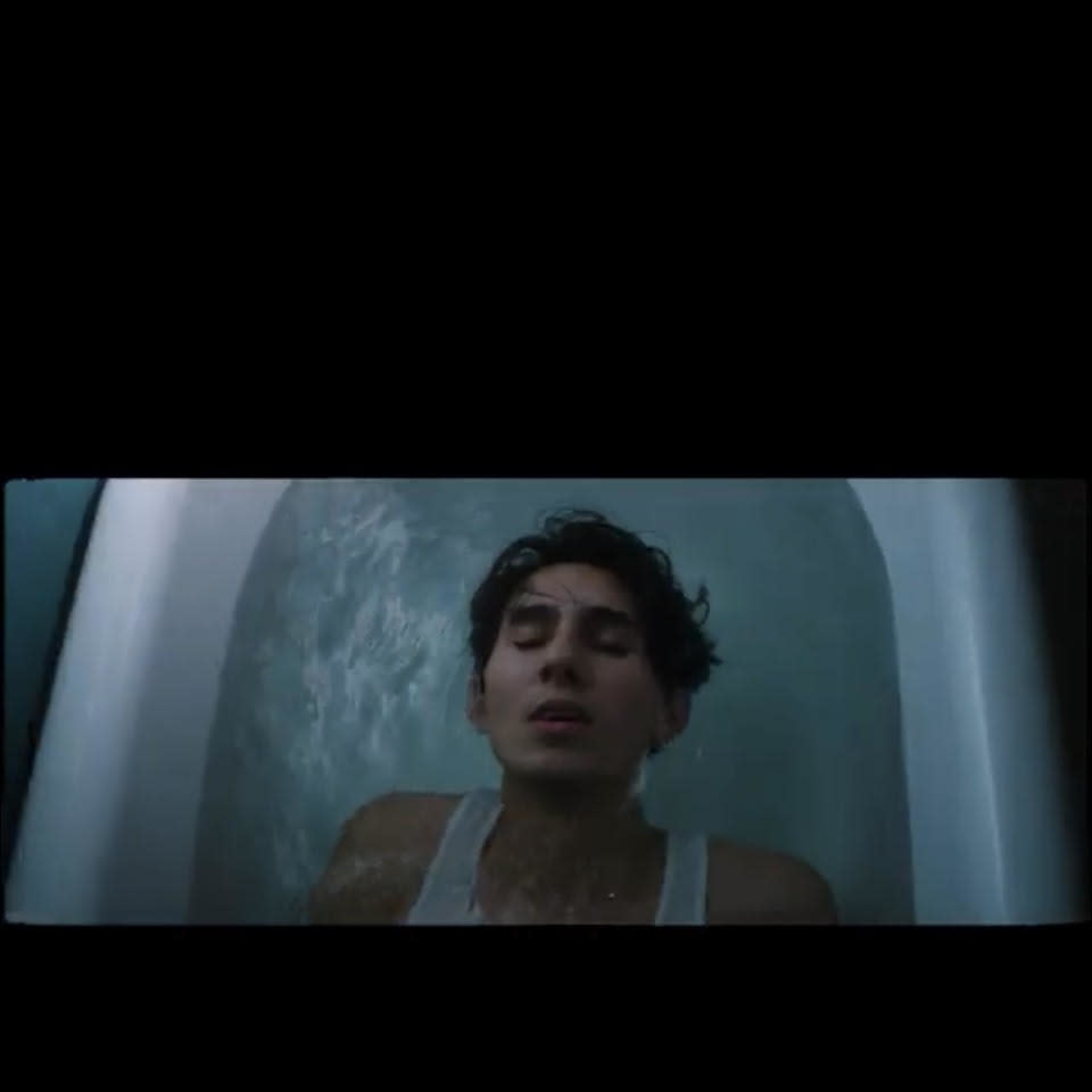 A person is submerged in a bathtub filled with water, appearing to be relaxed with their eyes closed.