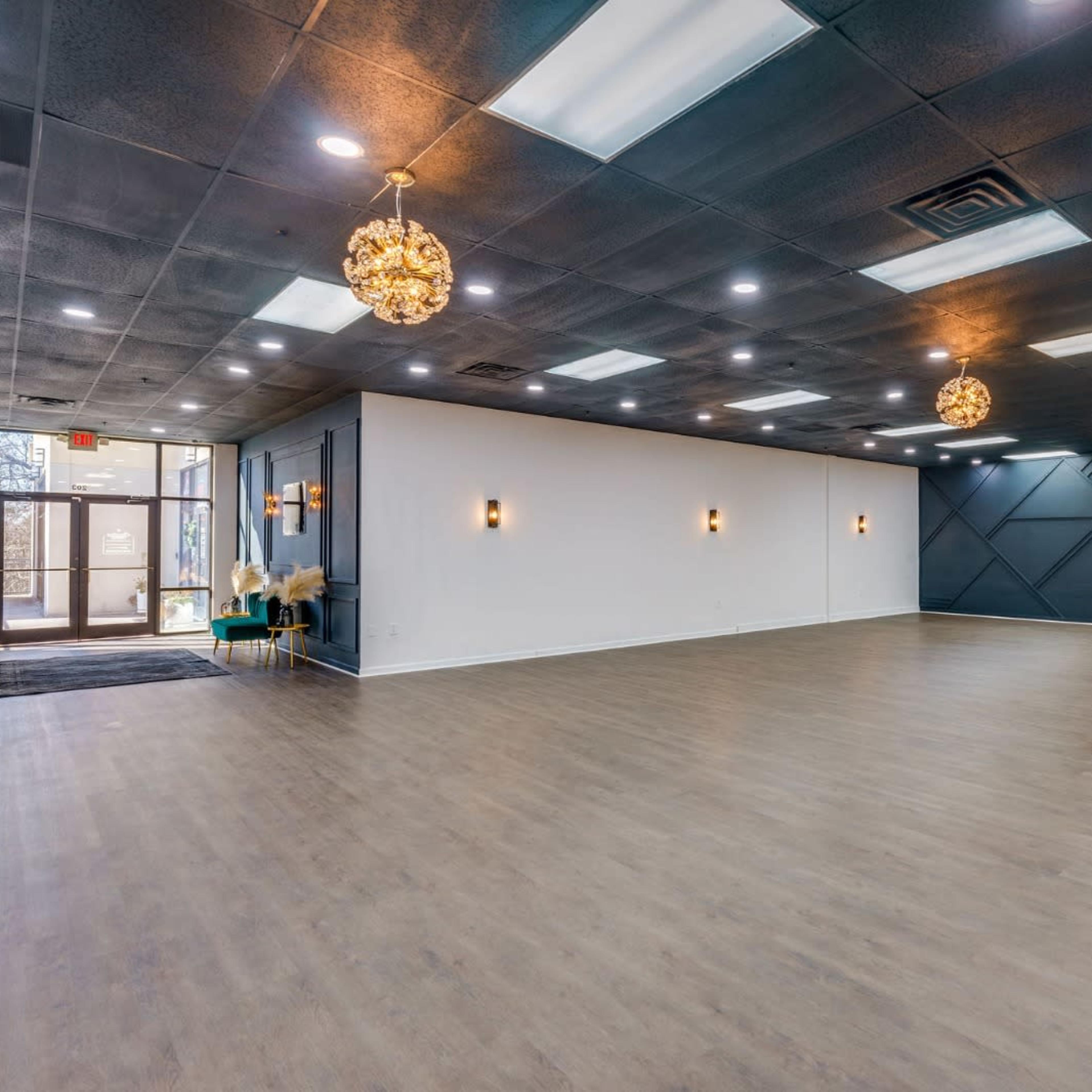 A spacious indoor venue with wooden flooring, high ceilings, and modern light fixtures.