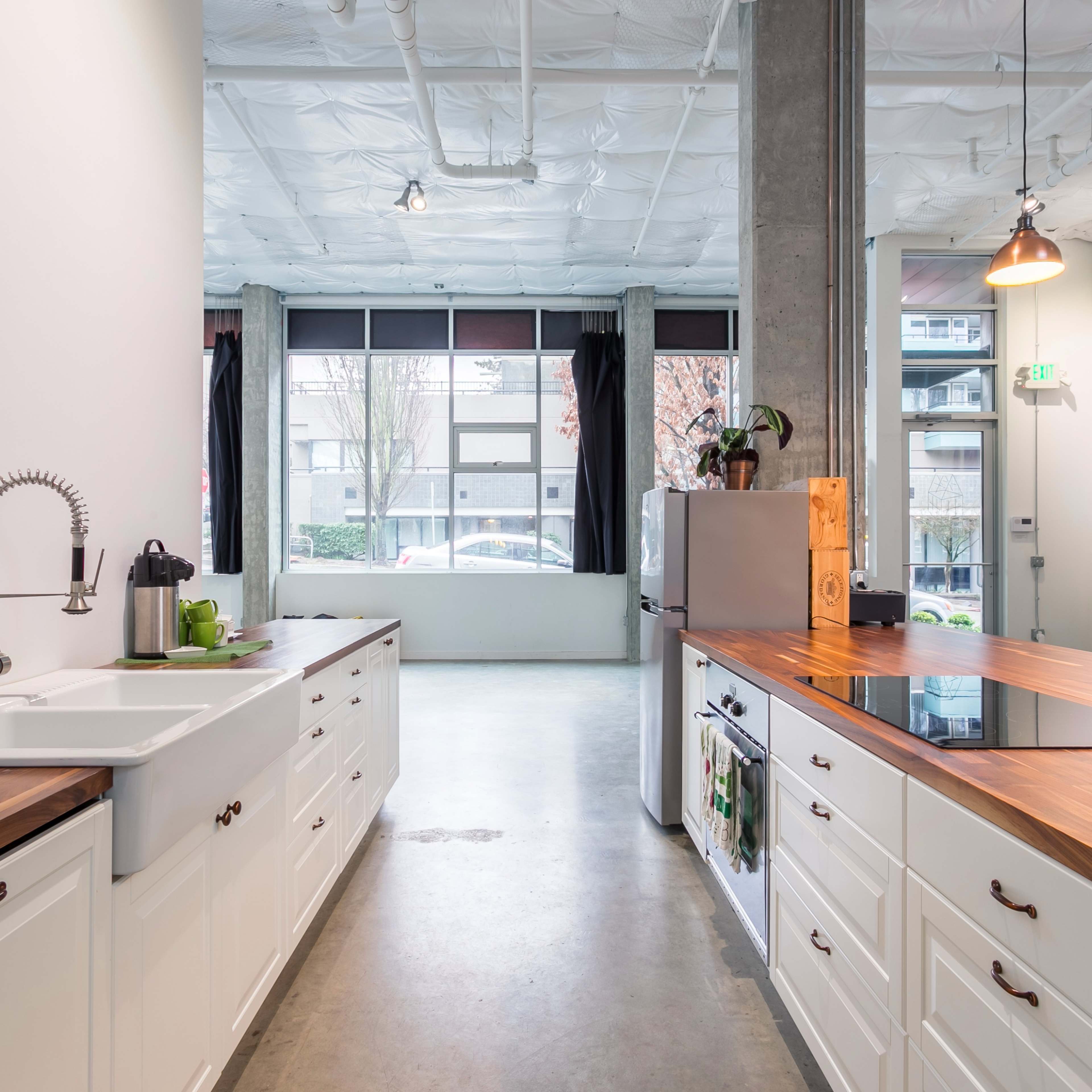 A modern kitchen featuring white cabinets, a wooden countertop, and a large window with natural light.