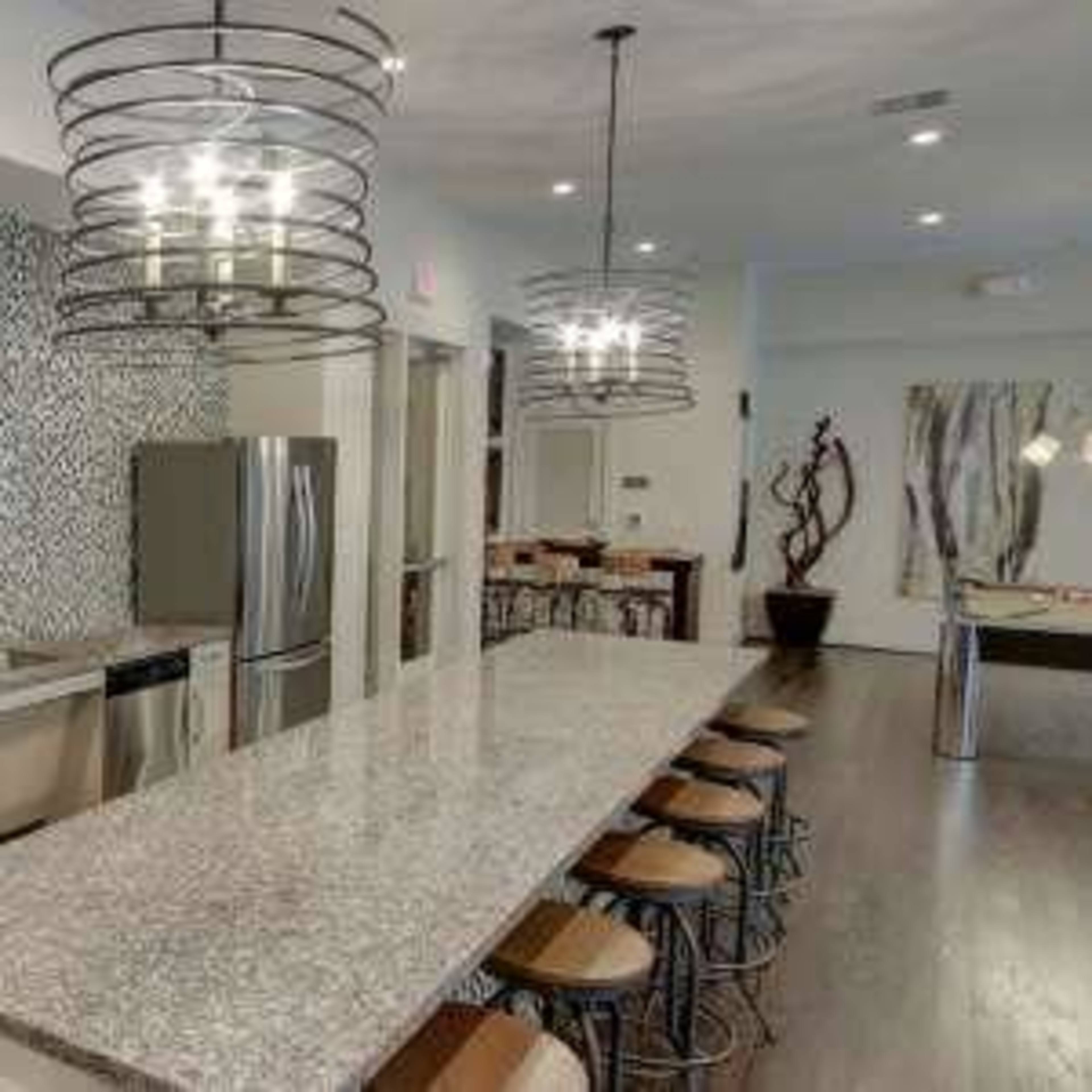 A modern kitchen with a granite island, stainless steel appliances, and a decorative tile backsplash.
