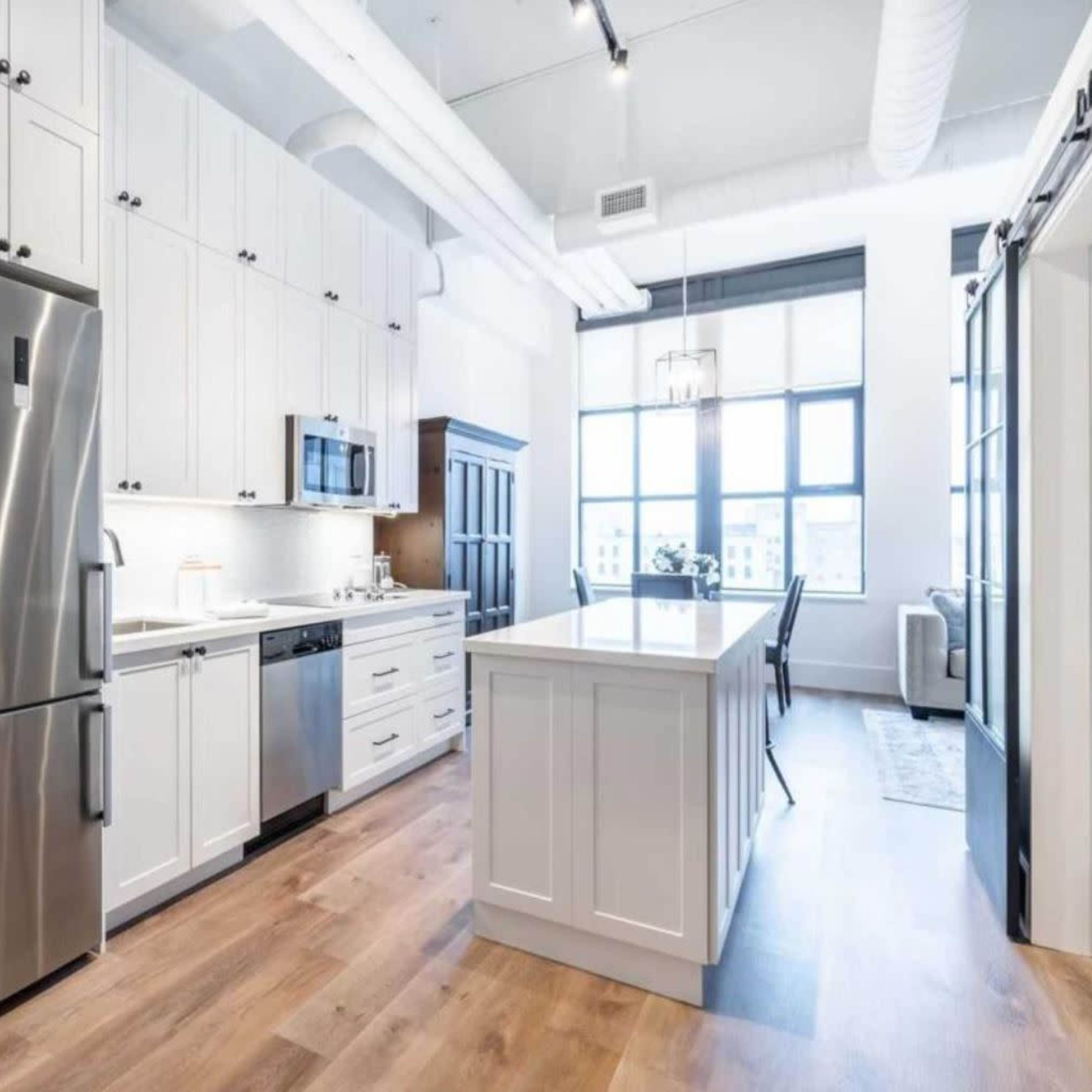 A modern kitchen with white cabinets, stainless steel appliances, and a central island with a light wood countertop.