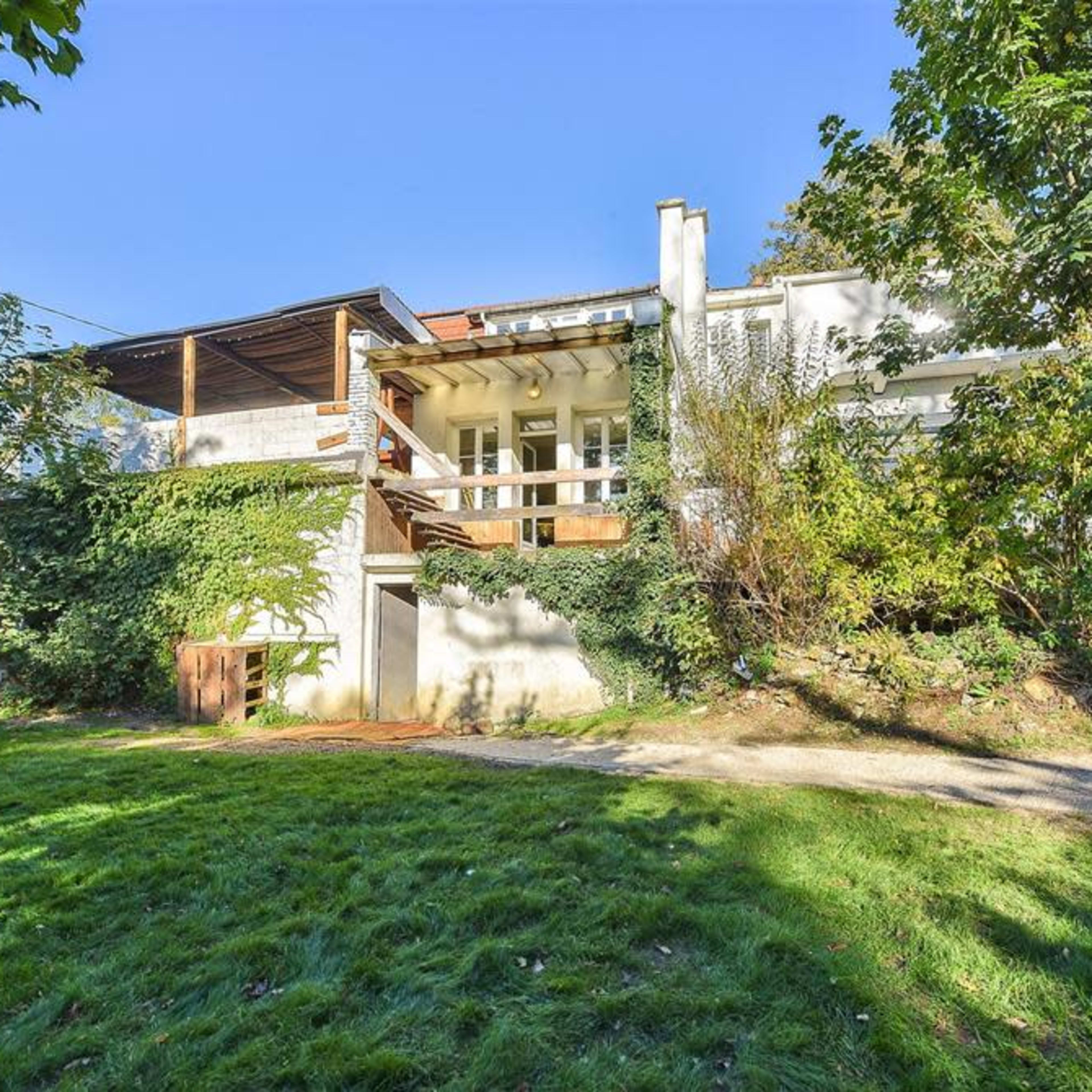 A modern two-story house surrounded by greenery and a well-maintained lawn.