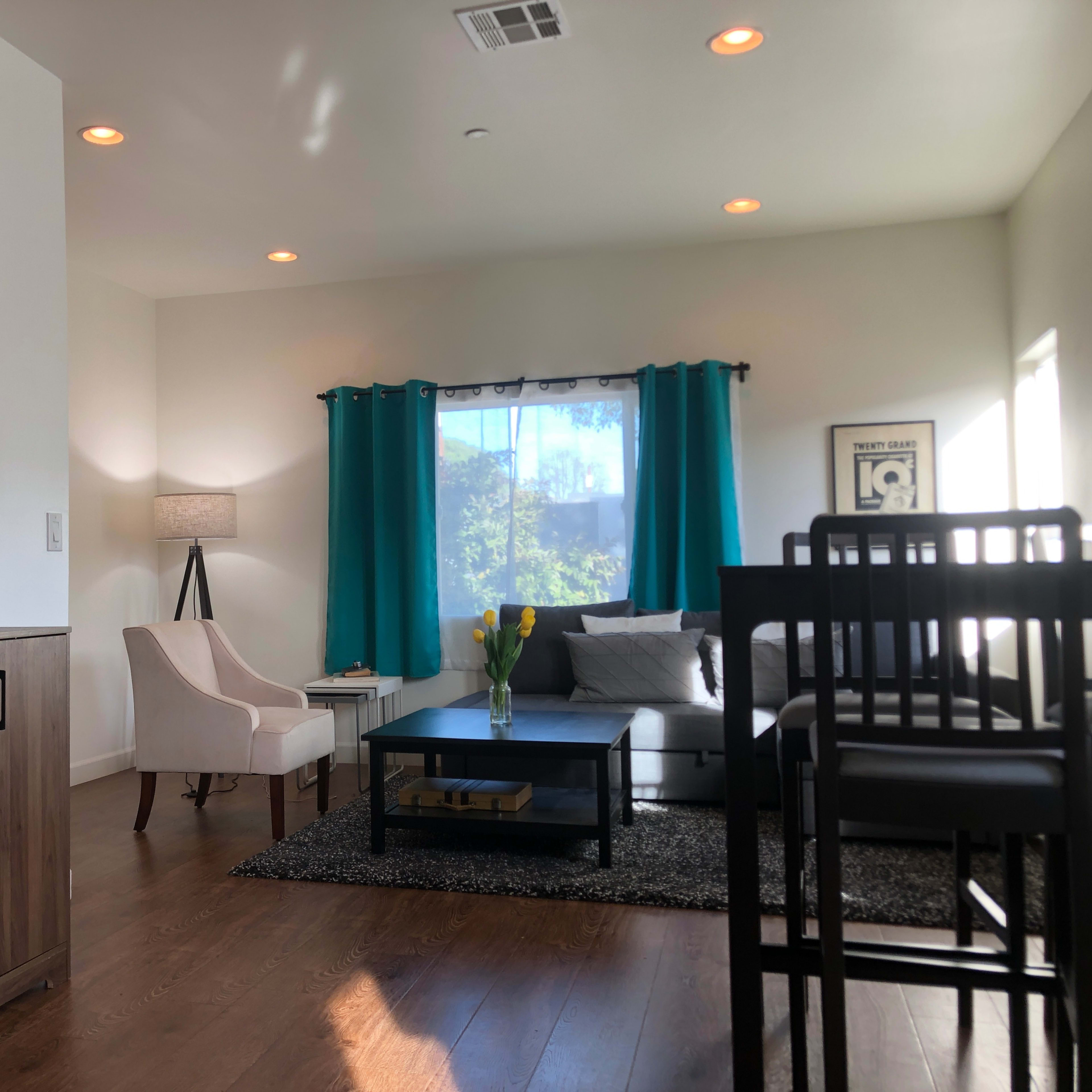 A modern living room with a light-colored sofa, a coffee table, and decorative elements, including a lamp and a bar cabinet.