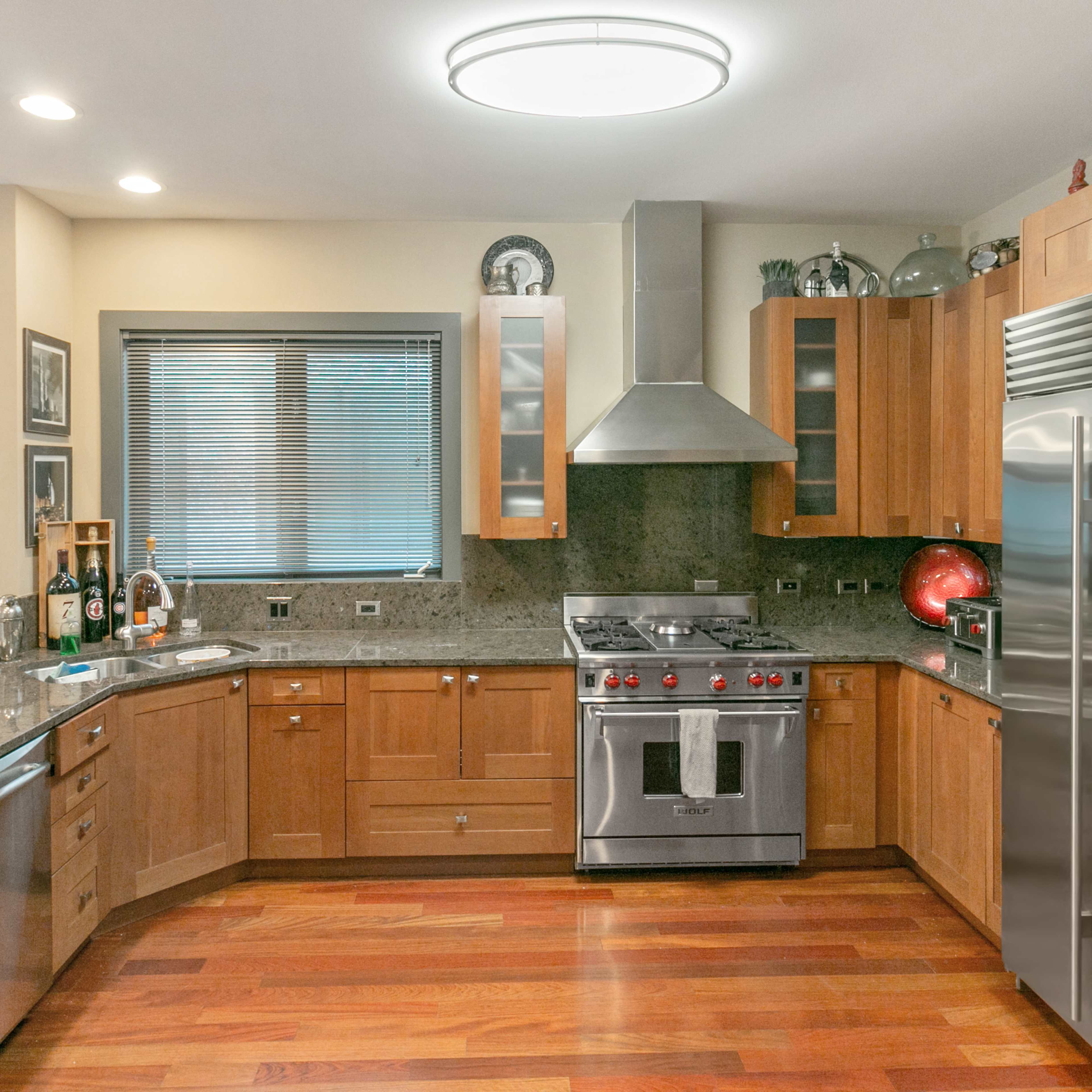 A modern kitchen features wooden cabinets, stainless steel appliances, and a granite countertop.