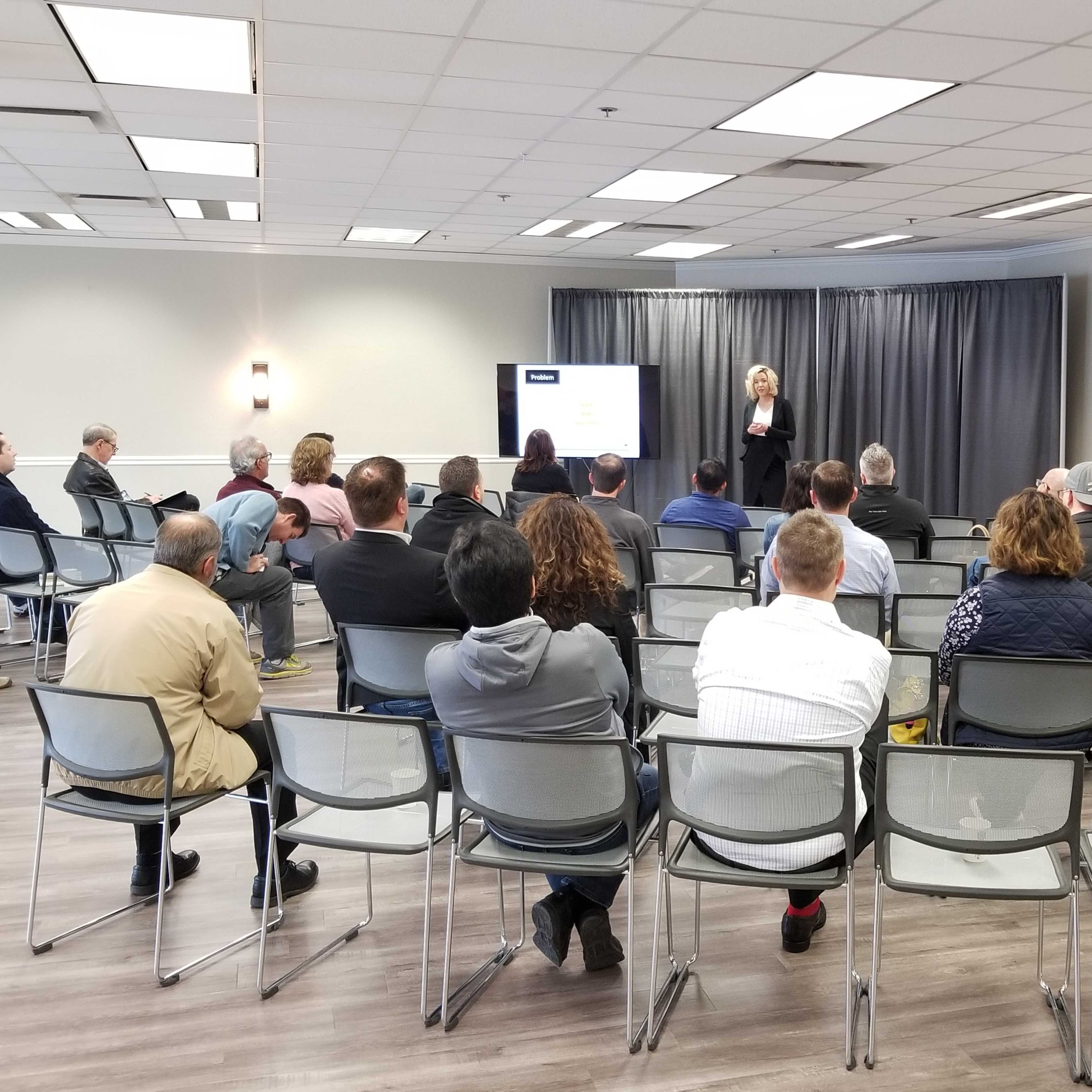A speaker presents to an audience seated in a conference room.