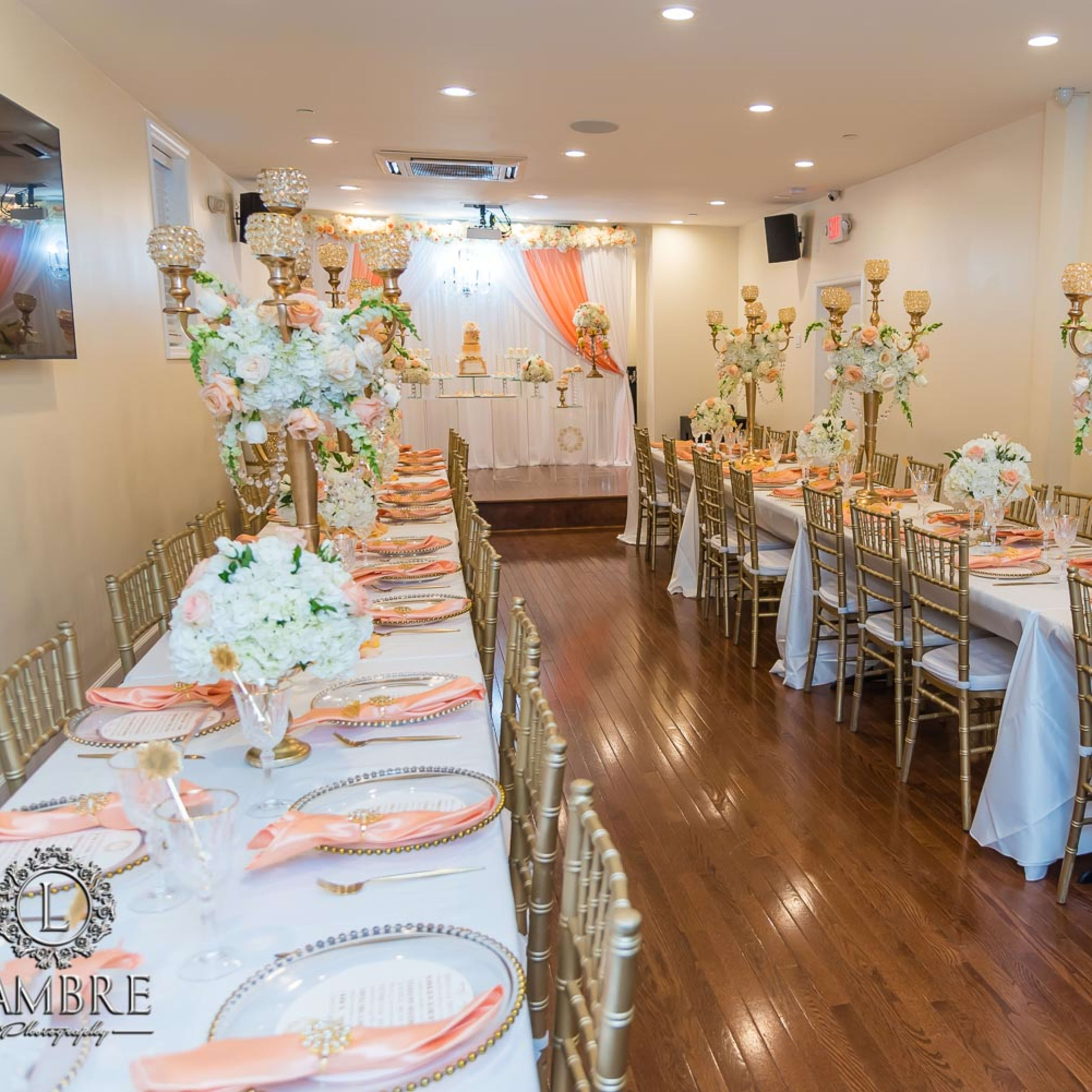 A banquet hall set for an event, featuring long tables adorned with floral centerpieces and golden chairs.