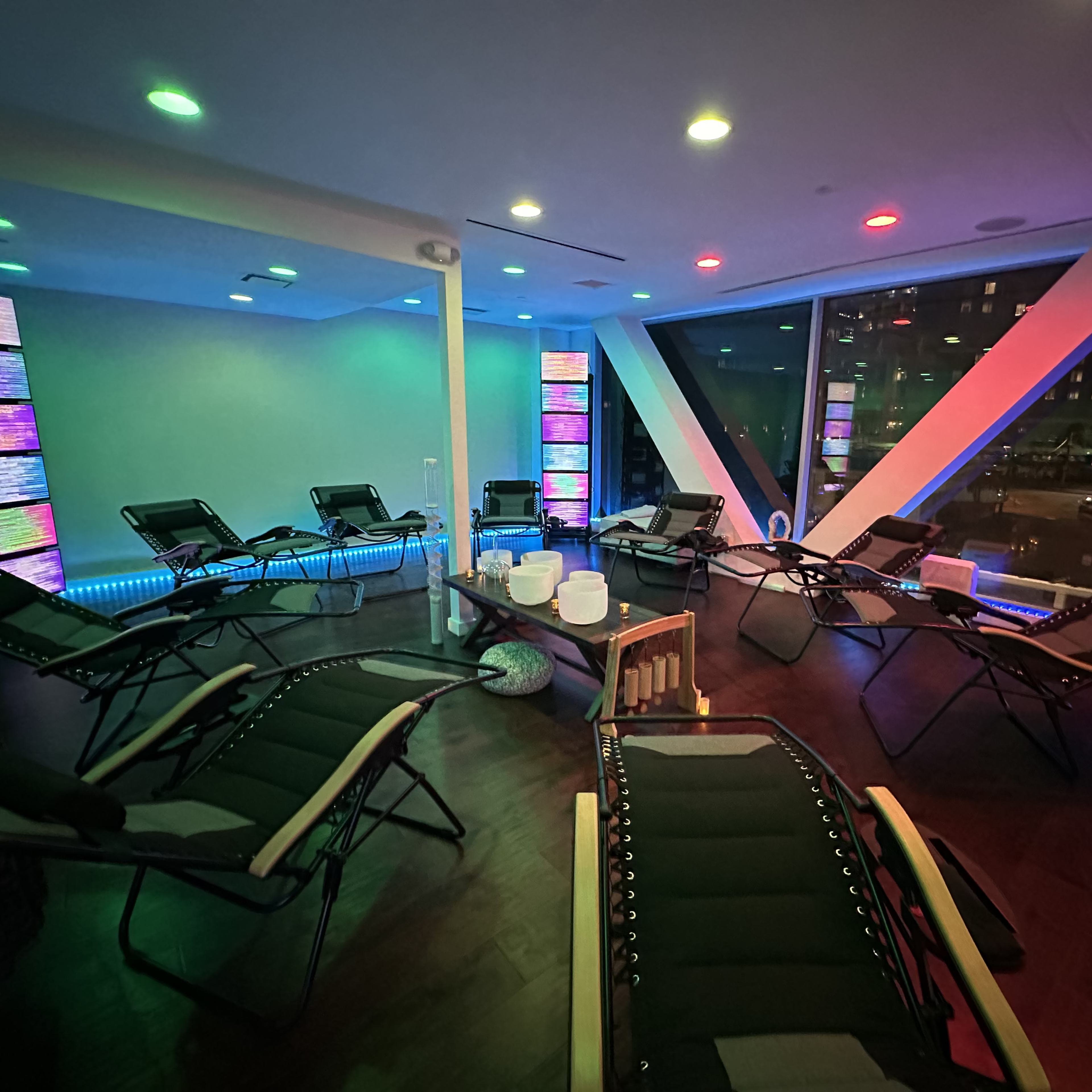 A modern relaxation room with reclining chairs, illuminated walls, and ambient lighting.
