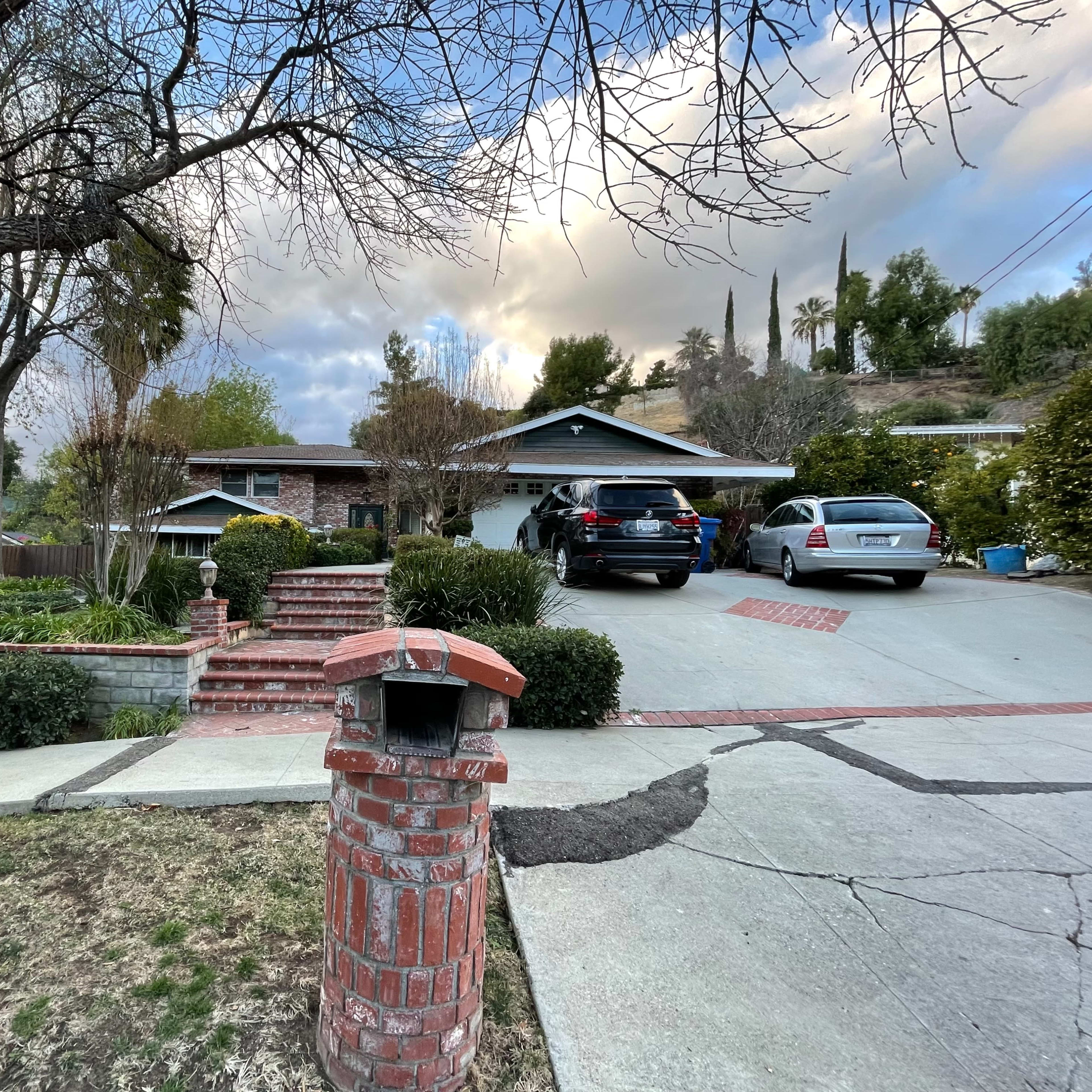 A residential home with a driveway accommodating two cars and a brick mailbox in the foreground.