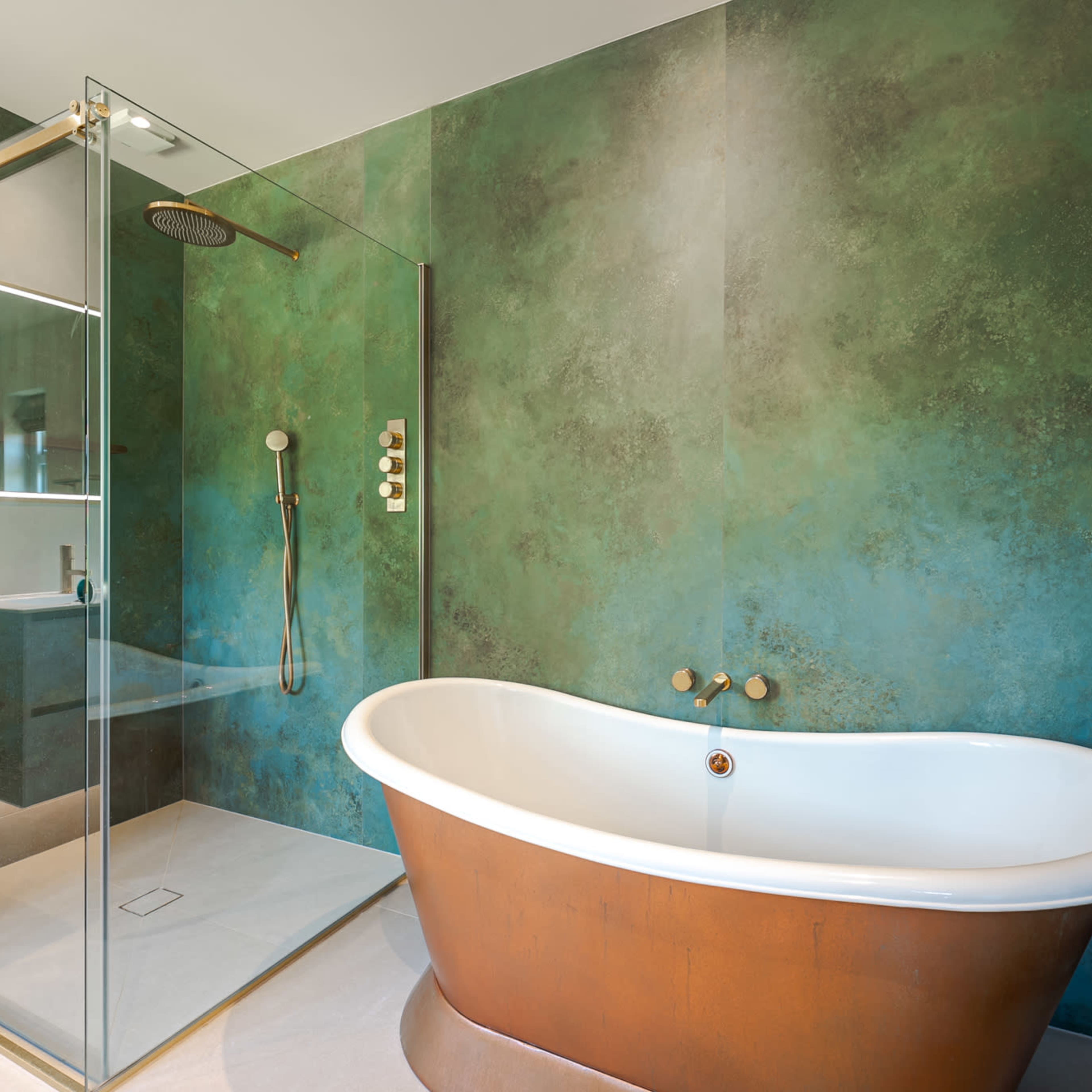 A modern bathroom with a freestanding white bathtub and a glass shower stall against a textured green wall.