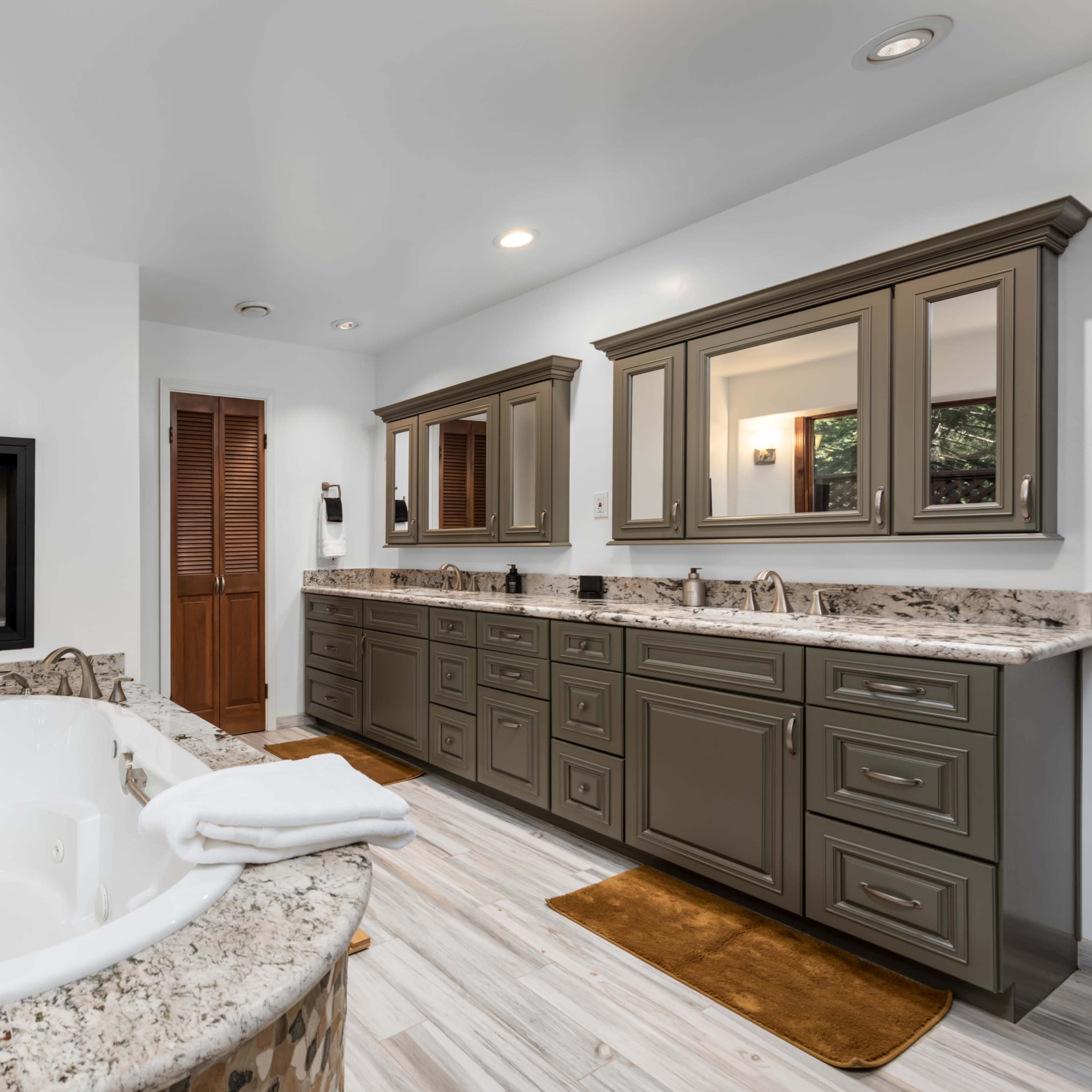 The bathroom features a modern design with a freestanding tub, dual vanities, a fireplace, and granite countertops.