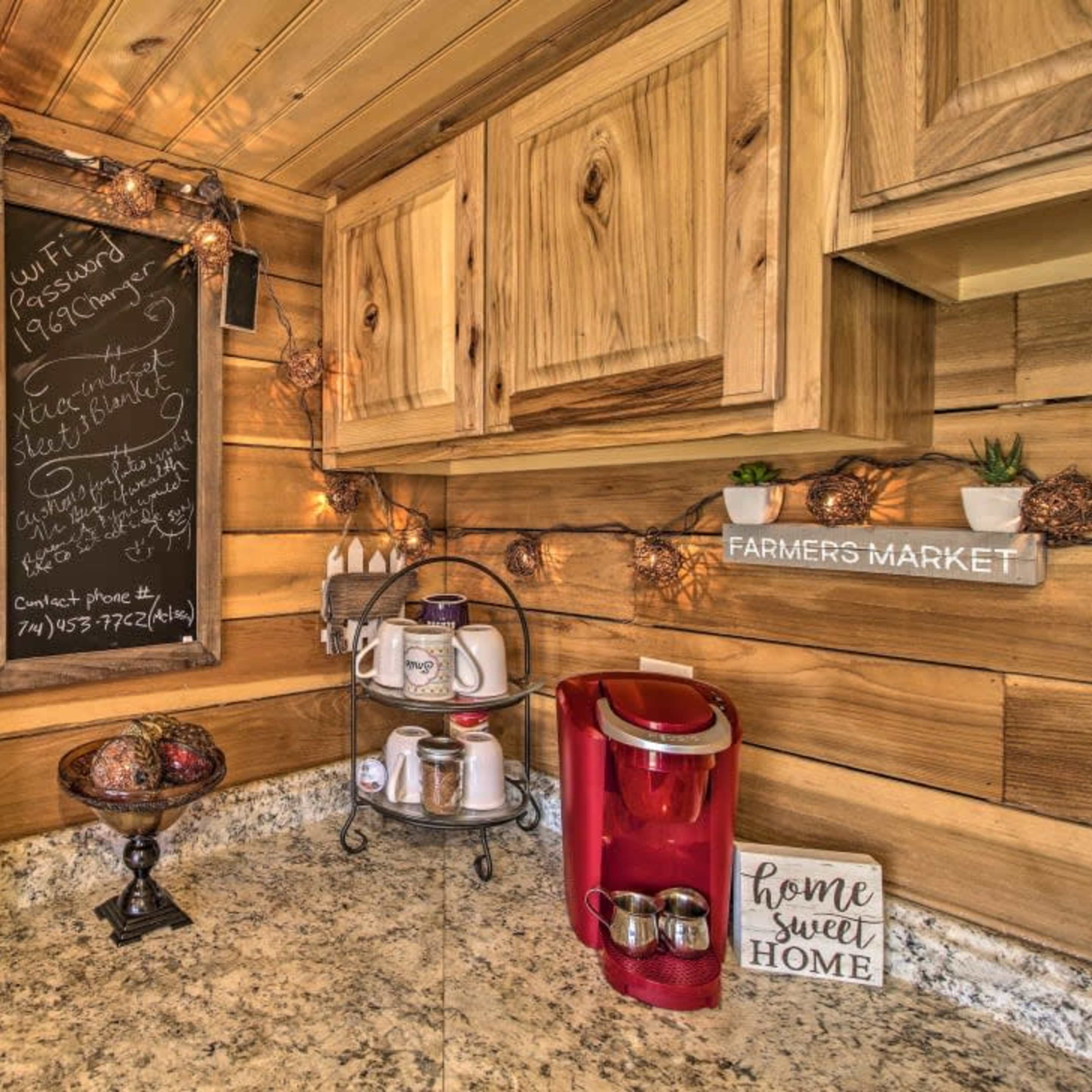 A rustic kitchen with wooden cabinets, a chalkboard, decorative items, and a coffee maker on a countertop.