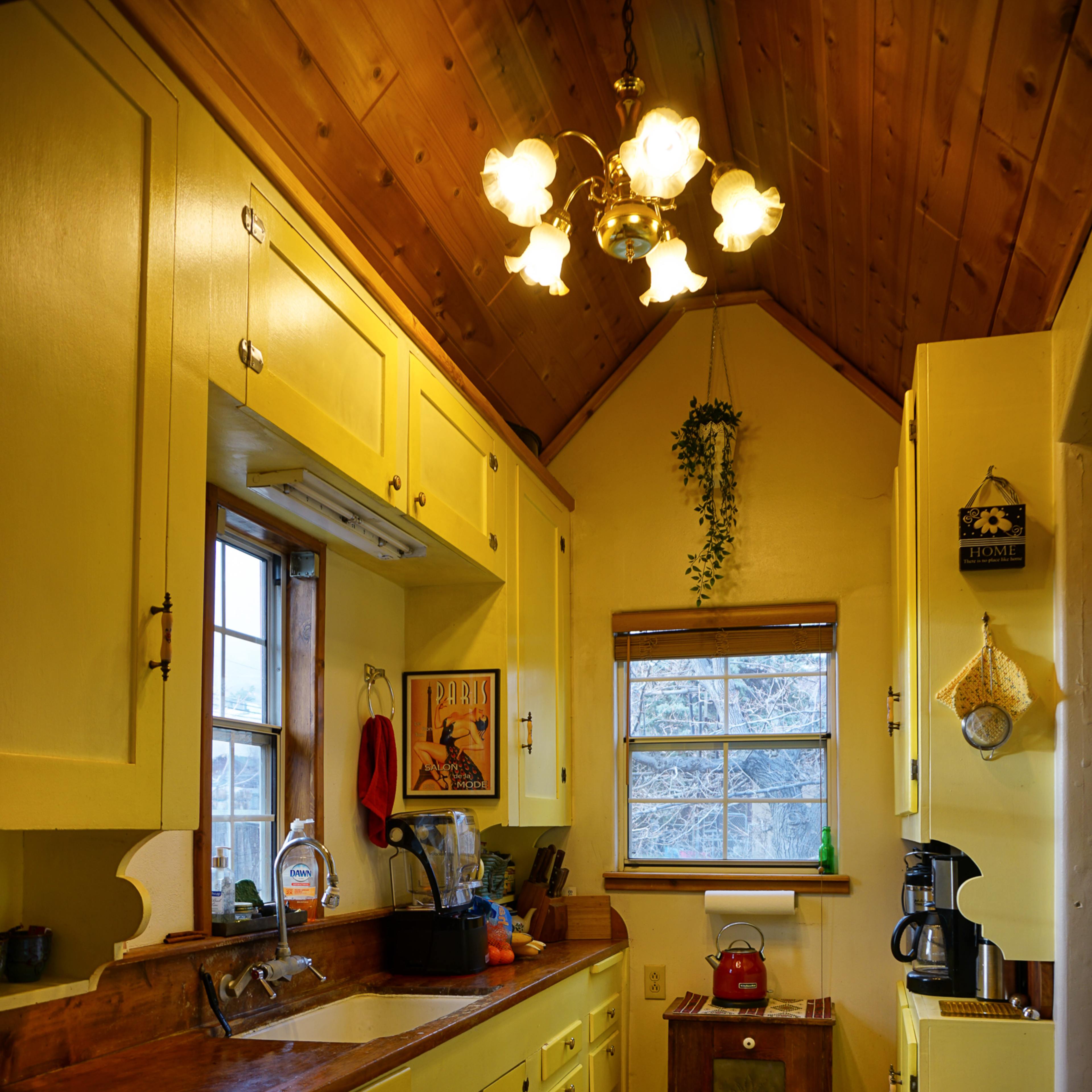The kitchen features yellow cabinets, a wooden countertop, and a window with natural light illuminating the space.
